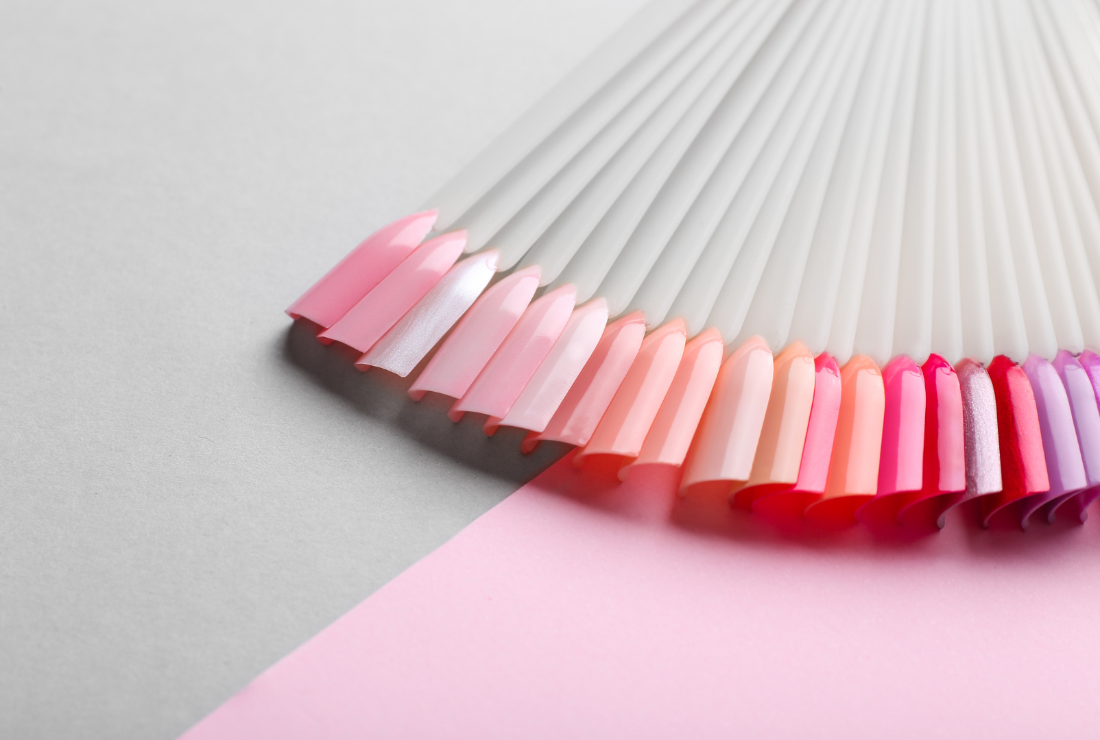 A woman is holding a jar of pink nail polish.