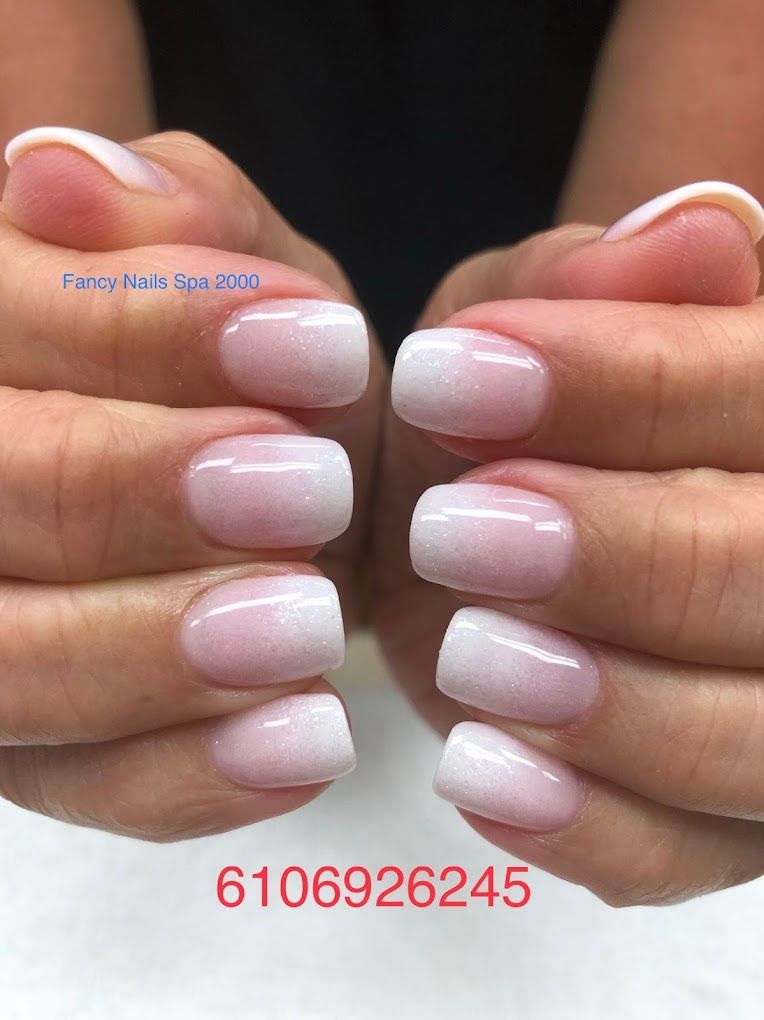 A close up of a woman 's nails with a french manicure.