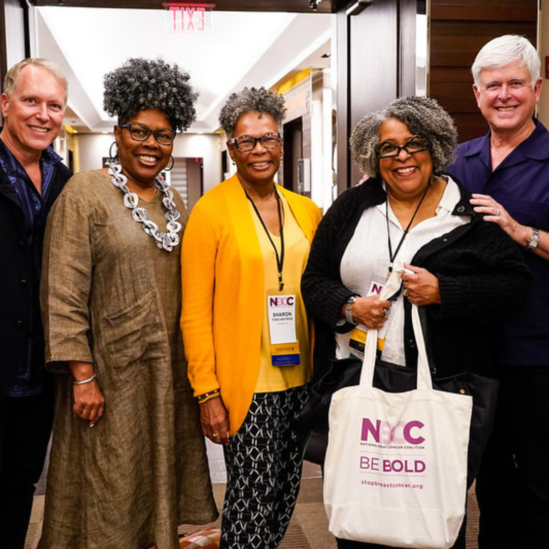 Five people stand together smiling in a doorway, including three wearing conference lanyards and a NBCC tote bag.