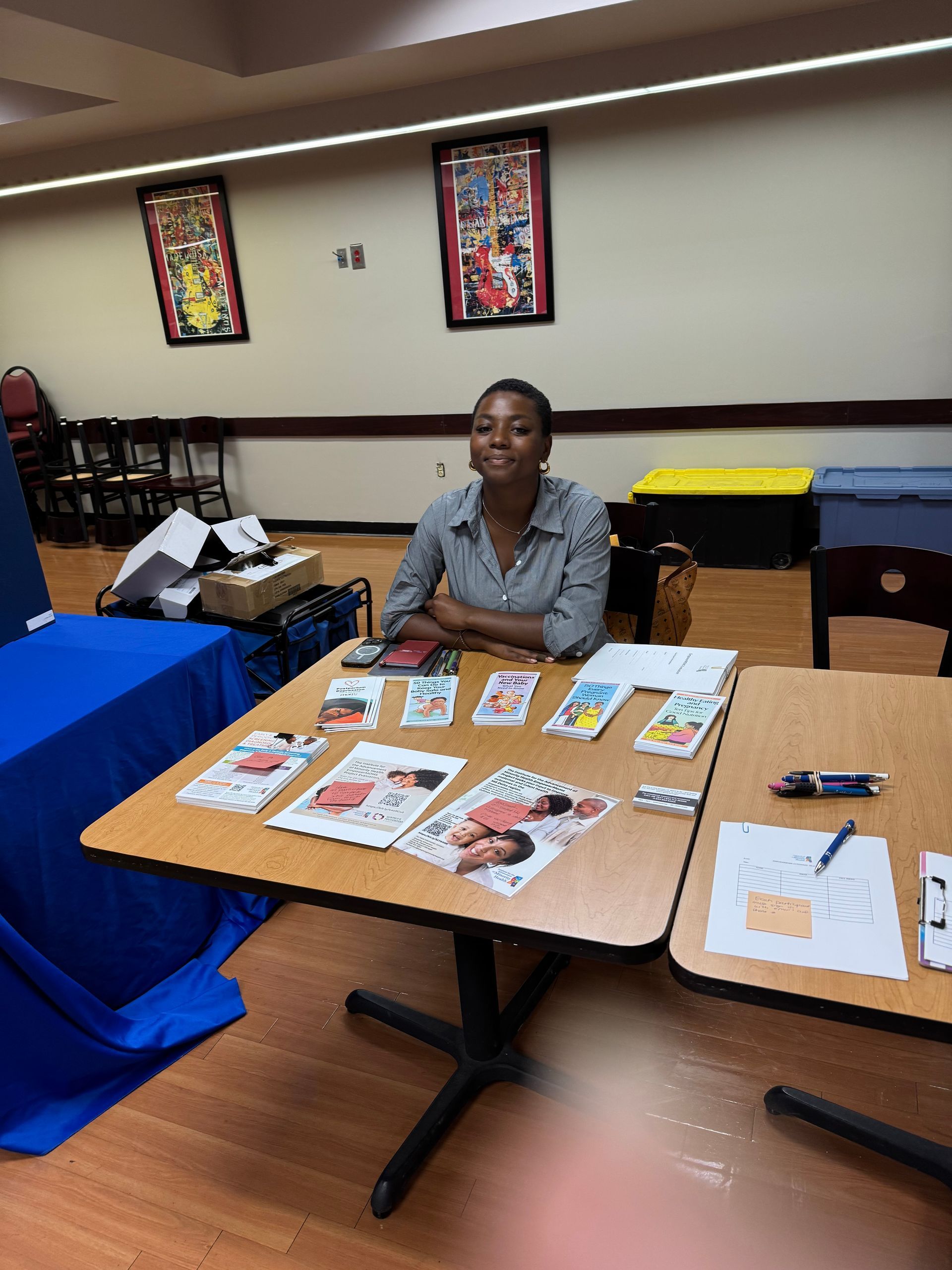 A person sits at a table displaying art prints and business cards in a room with posters.
