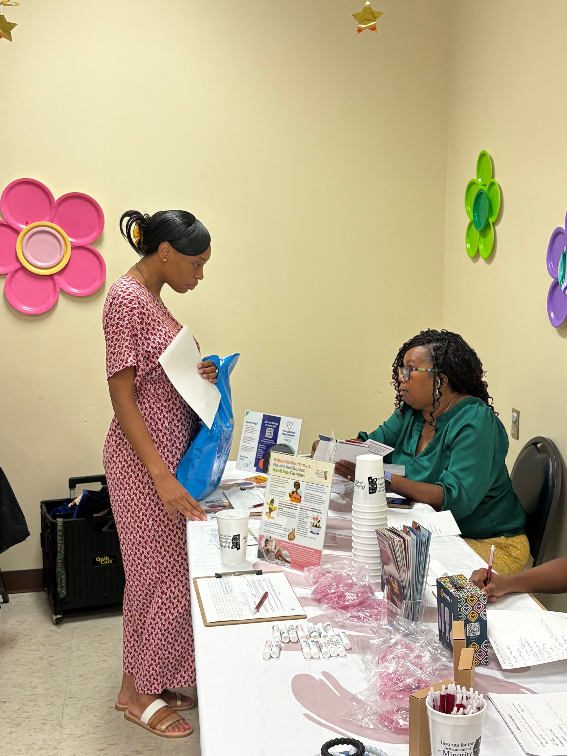 Group of people at a Minority Health event, posing near a promotional banner, smiles and table displays.