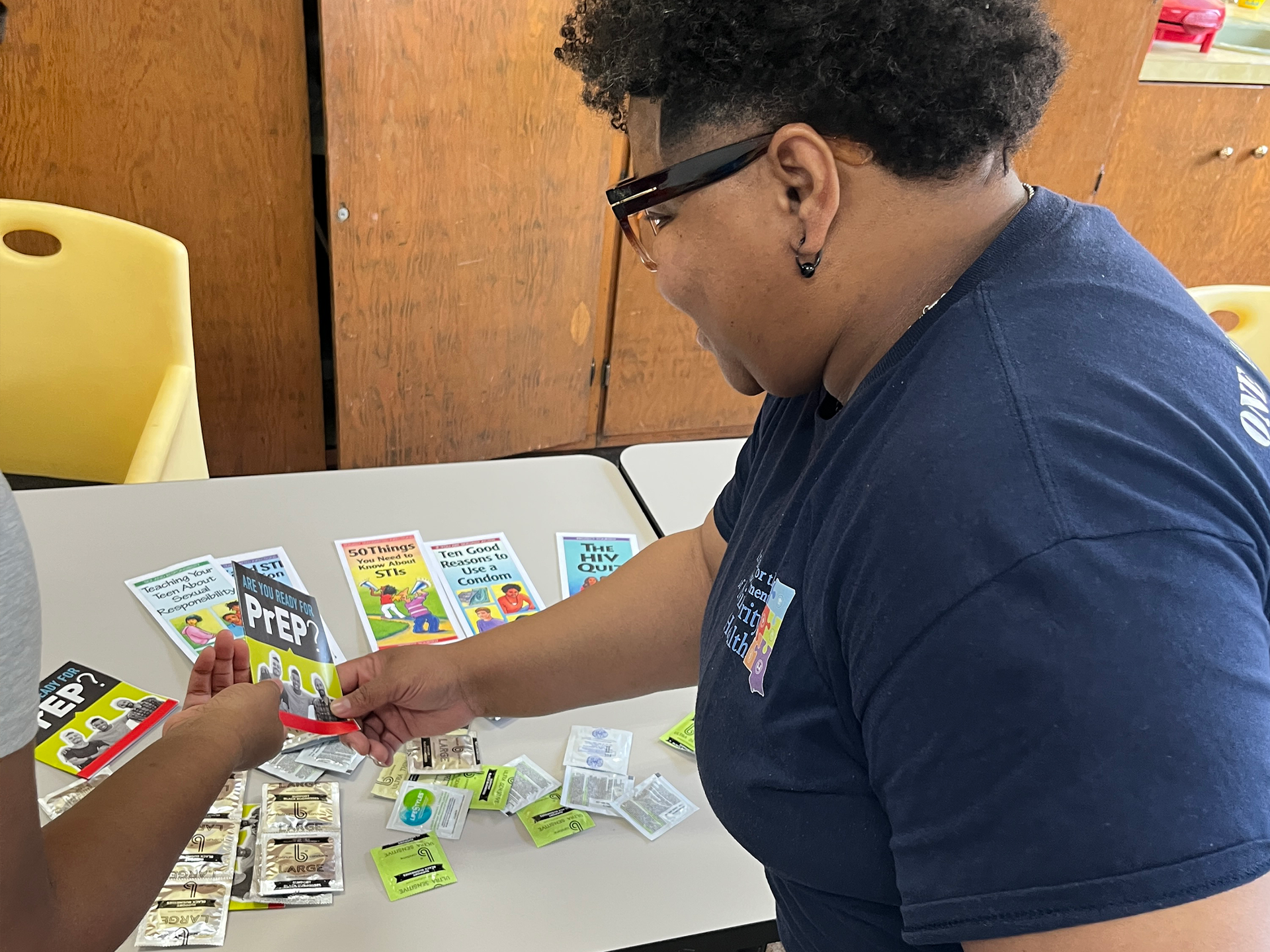 Woman with dreadlocks smiles at the camera, surrounded by people in red.