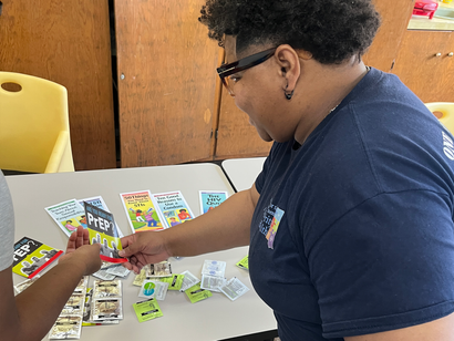 Woman with dreadlocks smiles at the camera, surrounded by people in red.