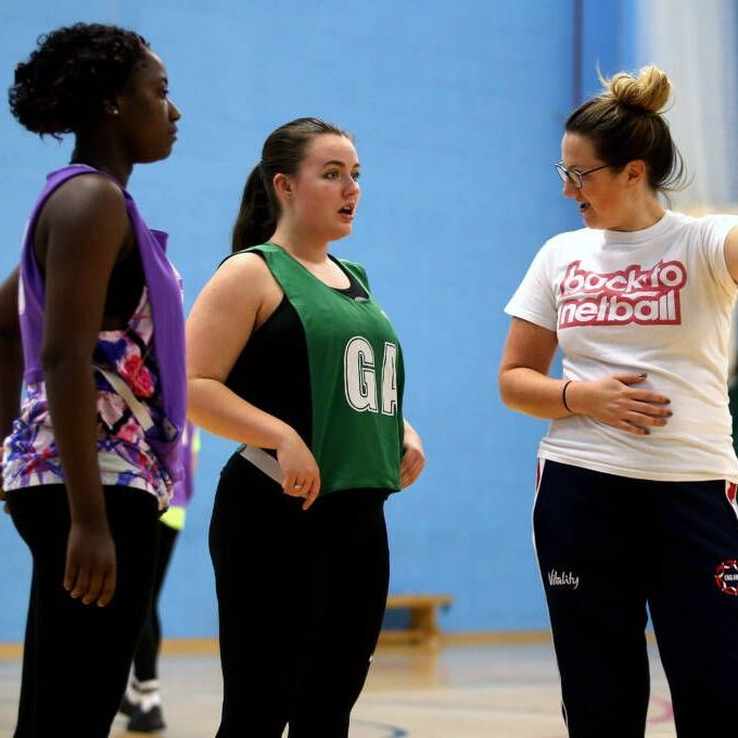 A woman wearing a back to netball shirt talks to two other women