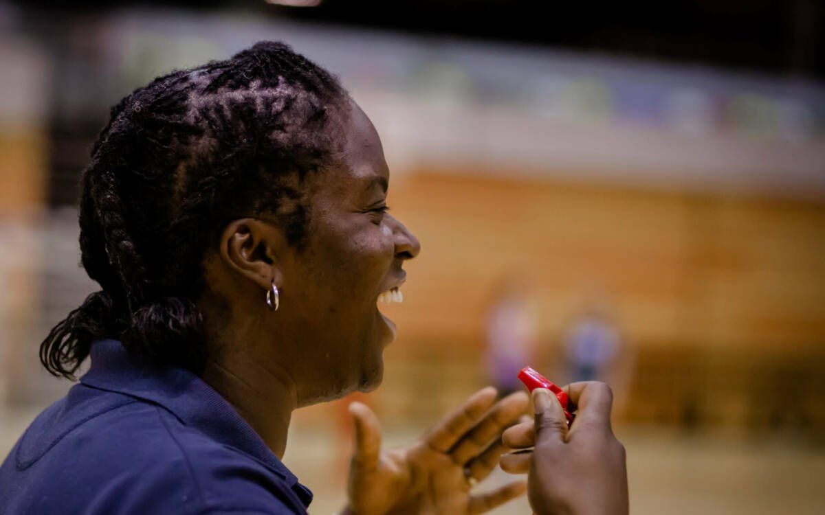 A woman is laughing while holding a red object in her hand.