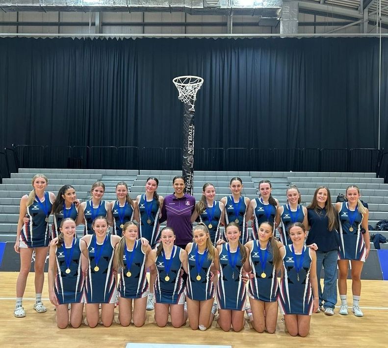 A group of girls are posing for a picture on a basketball court.