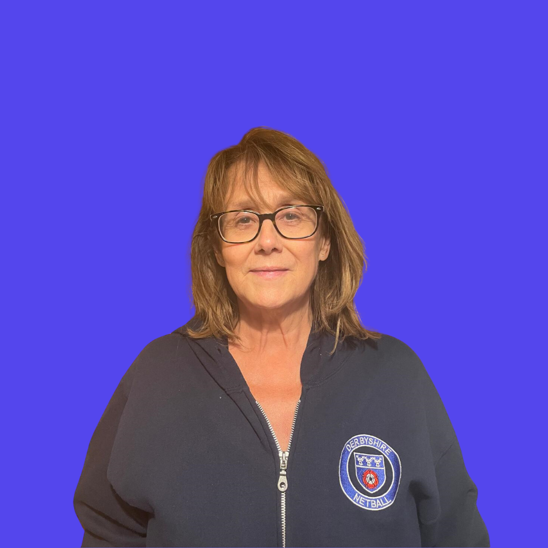 A woman wearing glasses is standing in front of a blue background.