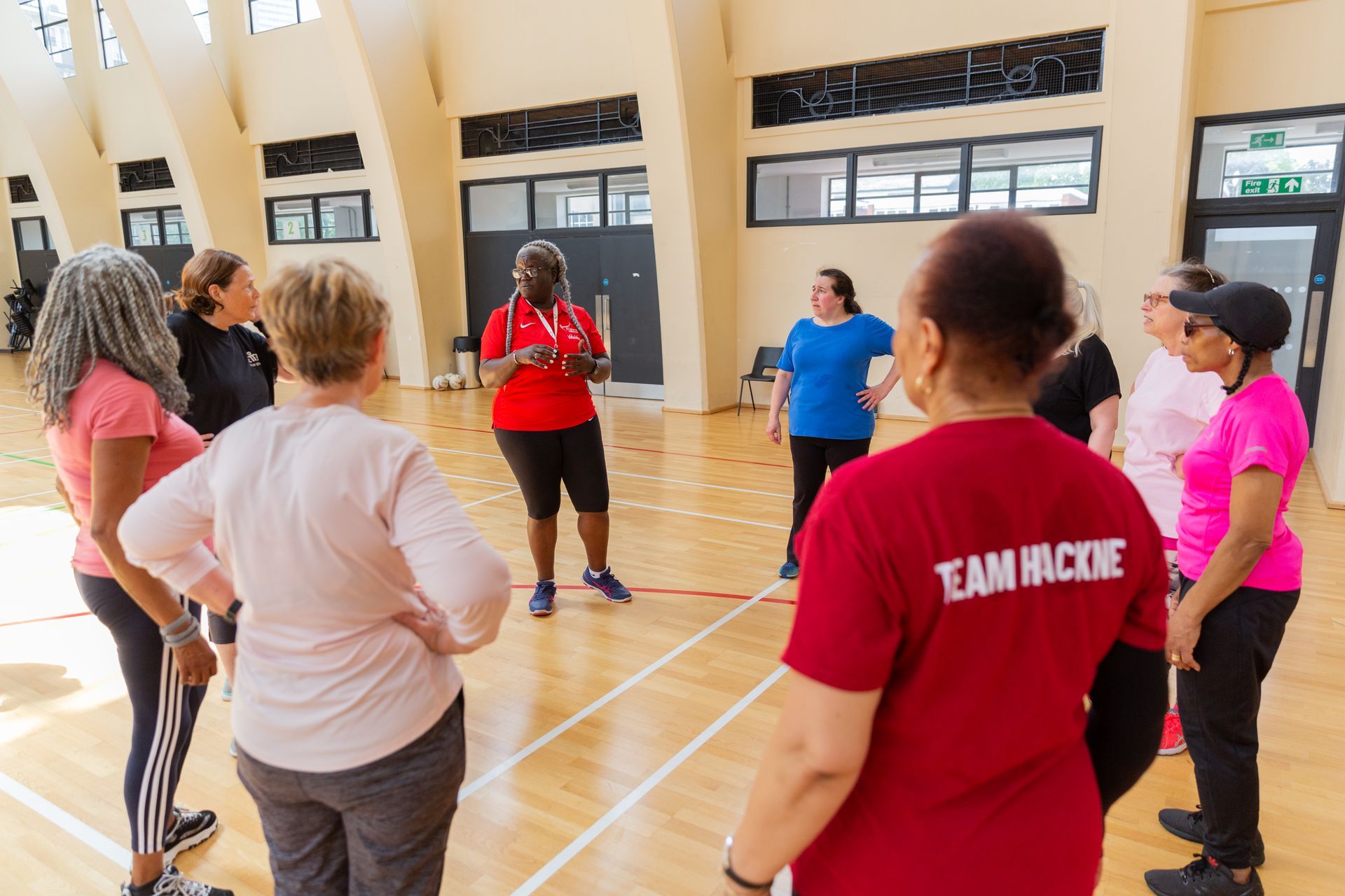 A group of women are standing in a circle on a basketball court.