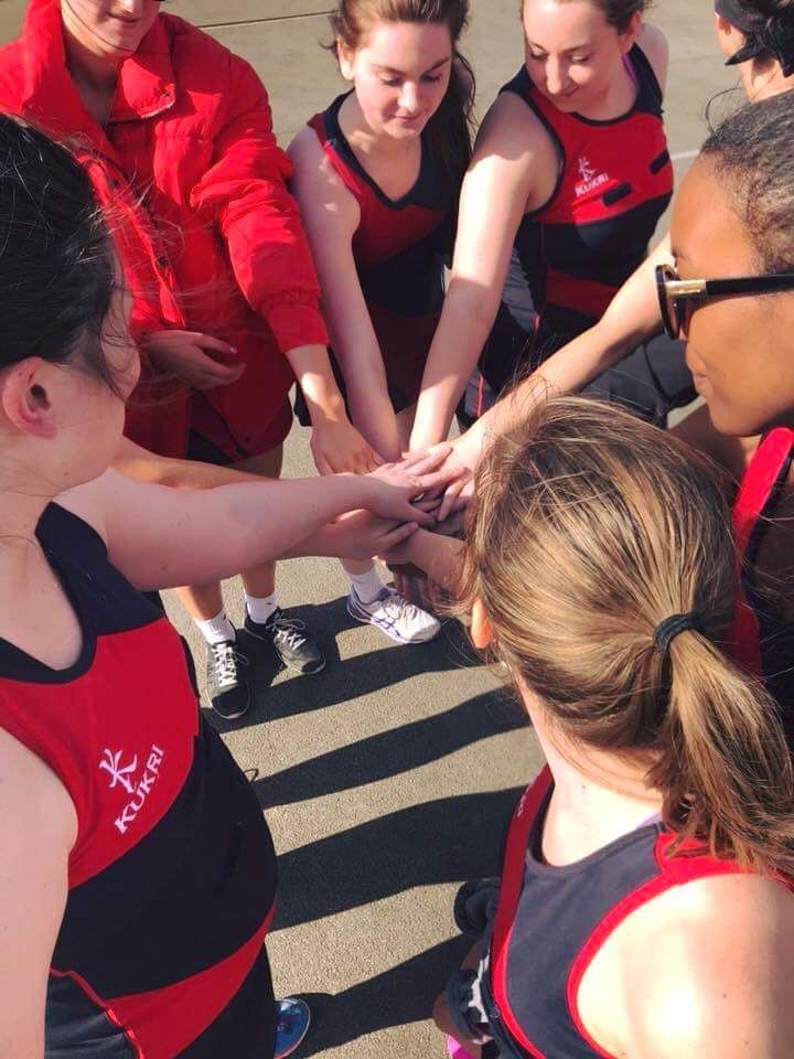 A group of girls are putting their hands together in a huddle