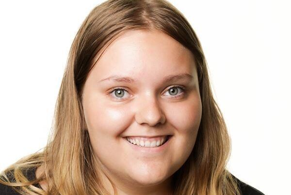 Et nærbillede af en kvindes smilende ansigt på en hvid baggrund.