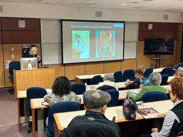 A group of people are sitting at tables in a room with a clock on the wall