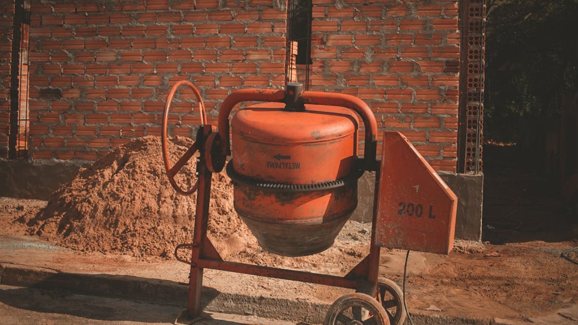 Una hormigonera está sentada delante de un montón de tierra.