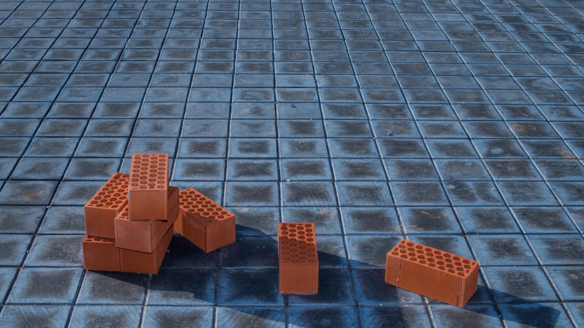 Una pila de ladrillos rojos sobre un suelo de baldosas azules.