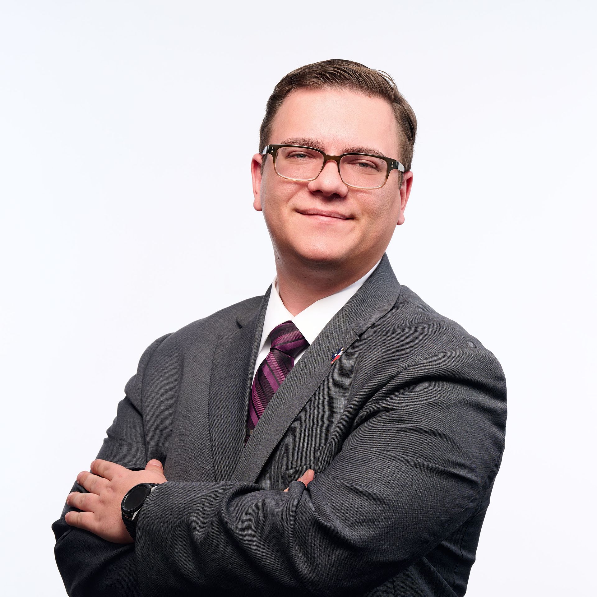 A man in a suit and red shirt is standing in front of a glass door