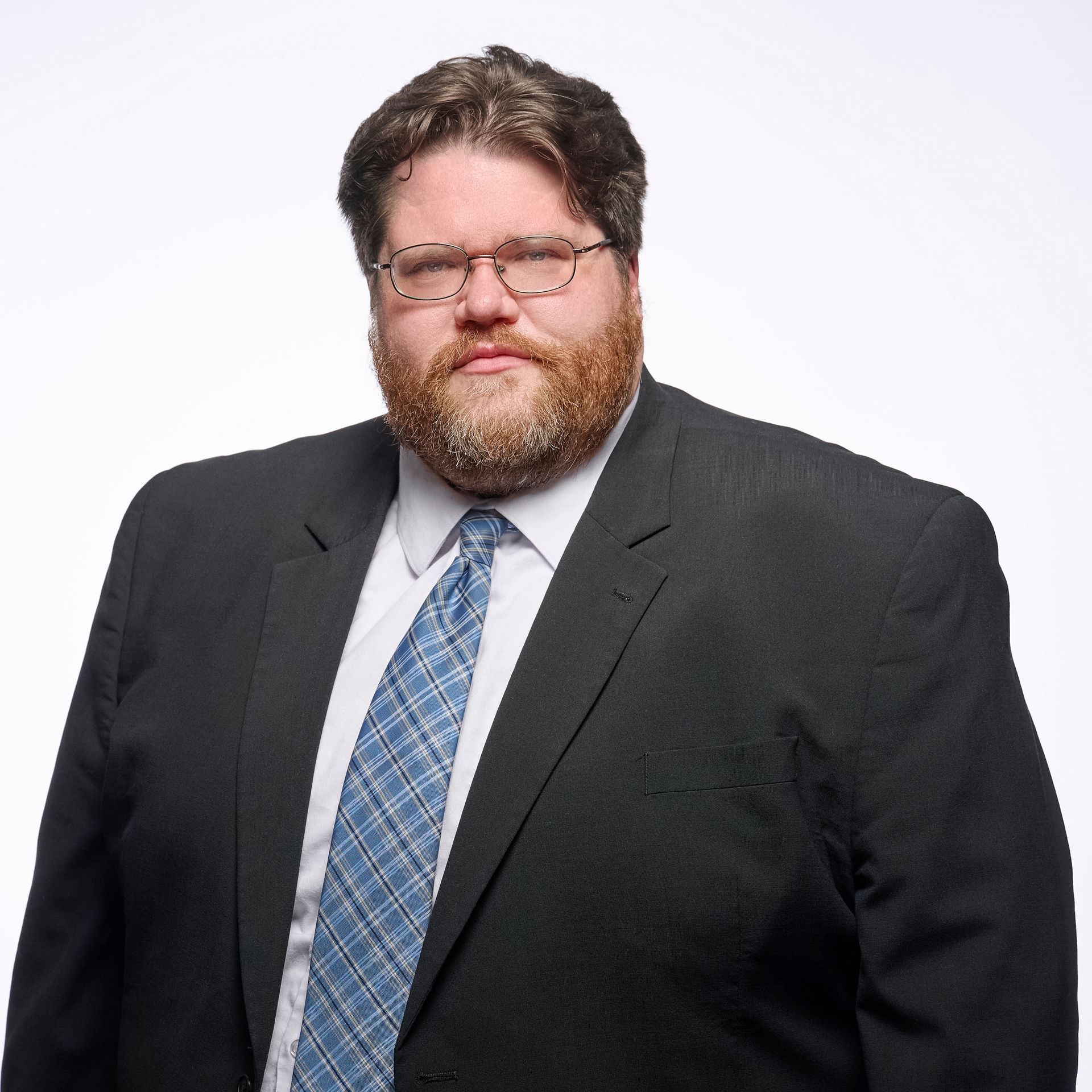 A man with a beard is wearing a blue suit and a watch.