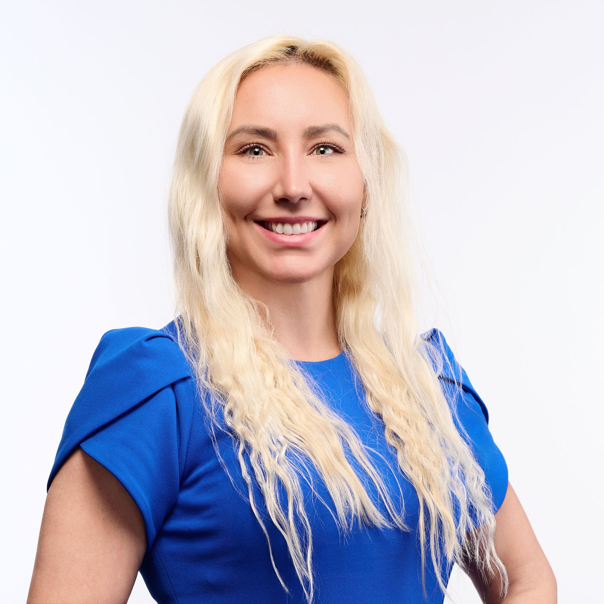 A woman in a black jacket is smiling in front of a door