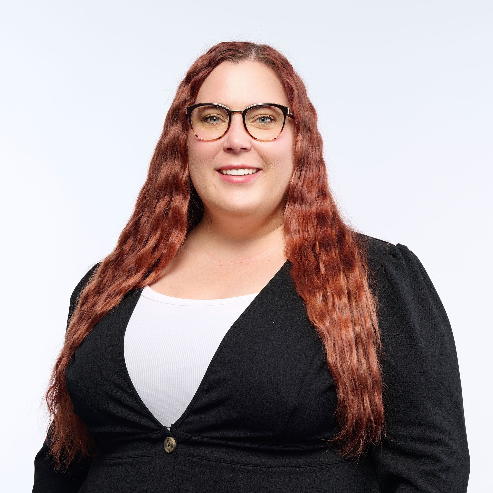 A woman in a gray jacket and black shirt is smiling for the camera.