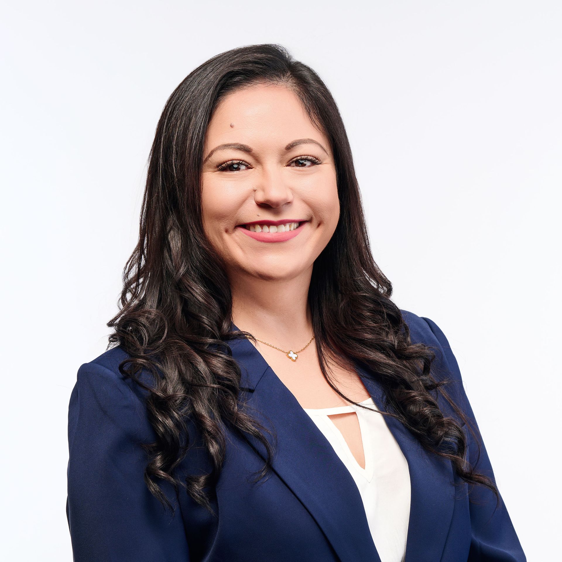 A woman in a black jacket is smiling in front of a door
