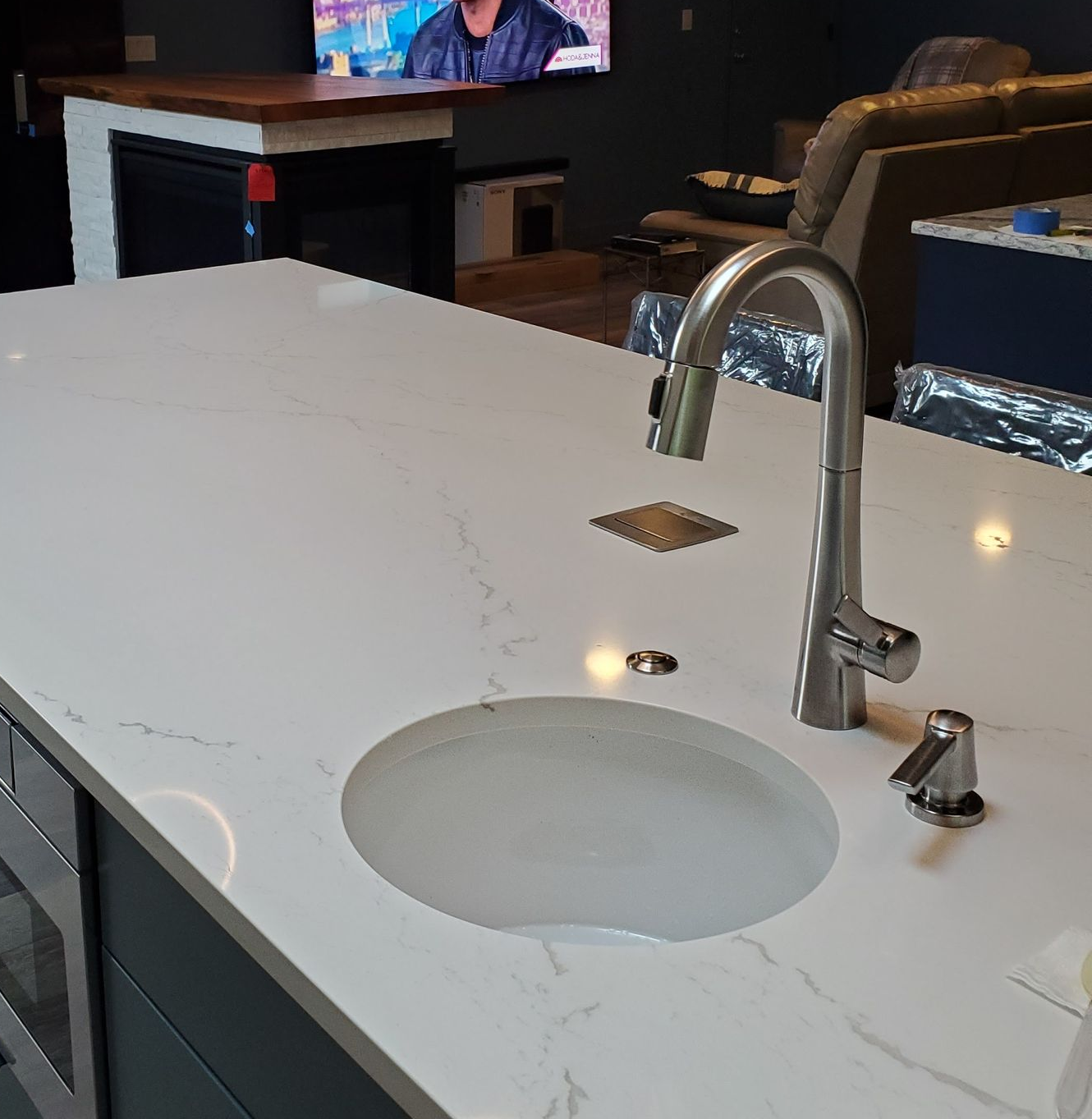 Kitchen island with a white countertop and a stainless steel faucet.