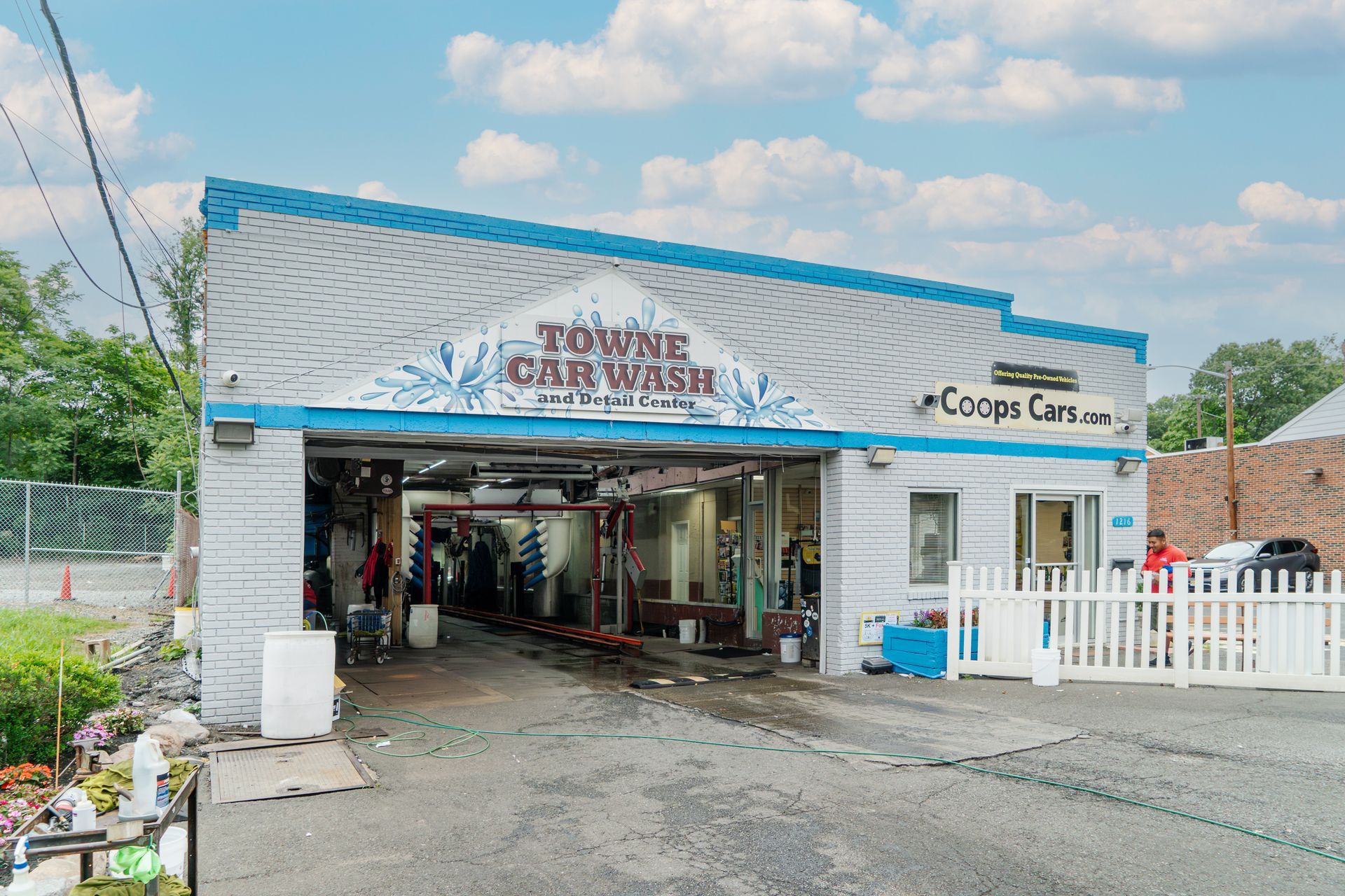 A car wash with a white picket fence in front of it.