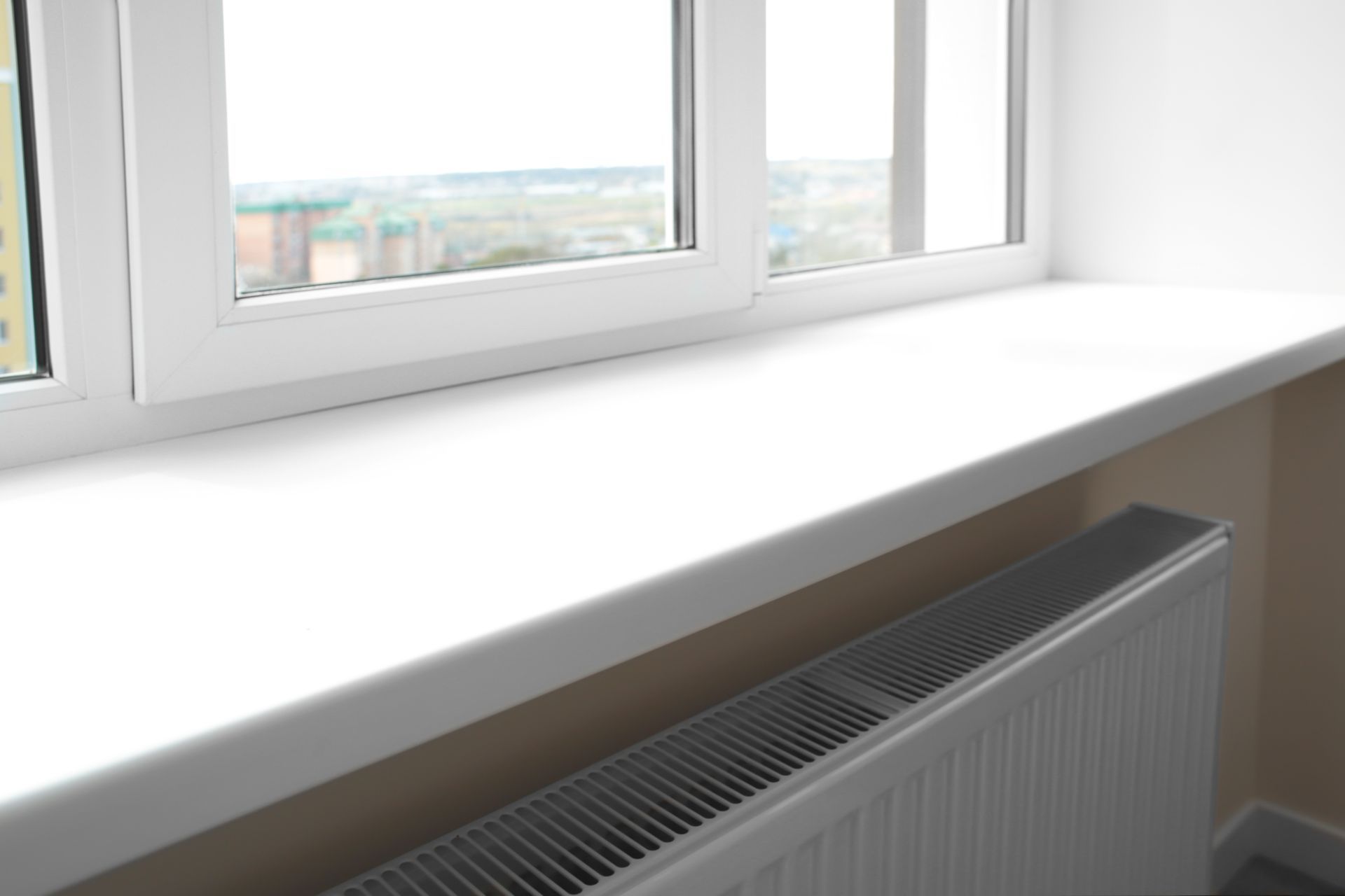 Unterhalb eines geschlossenen Fensters befindet sich eine weiße Fensterbank aus Kunststoff