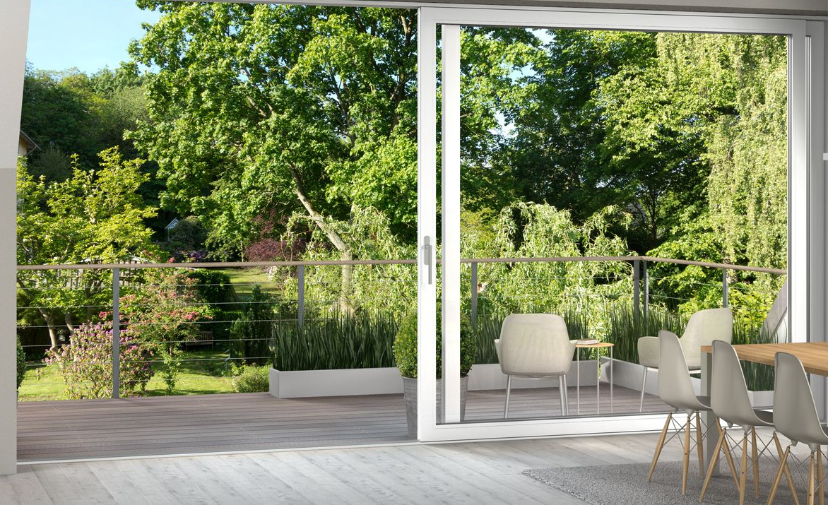 gemütliche Ecke mit einem grauen Sessel, einer Stehlampe mit Dreibeinständer vor bodentiefen Fenstern mit Jalousien.