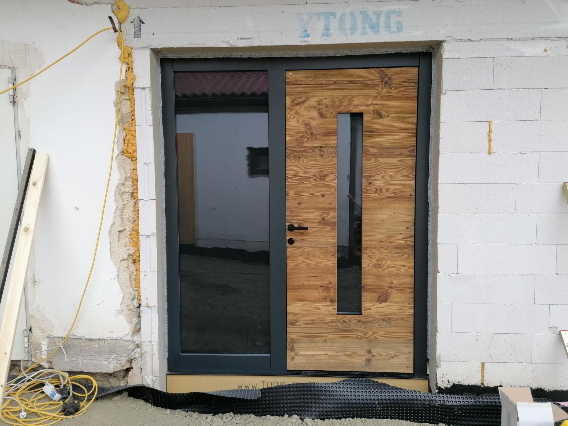 hölzerne Eingangstür mit vertikalen Glasscheibe und einer seitlichen Glasscheibe