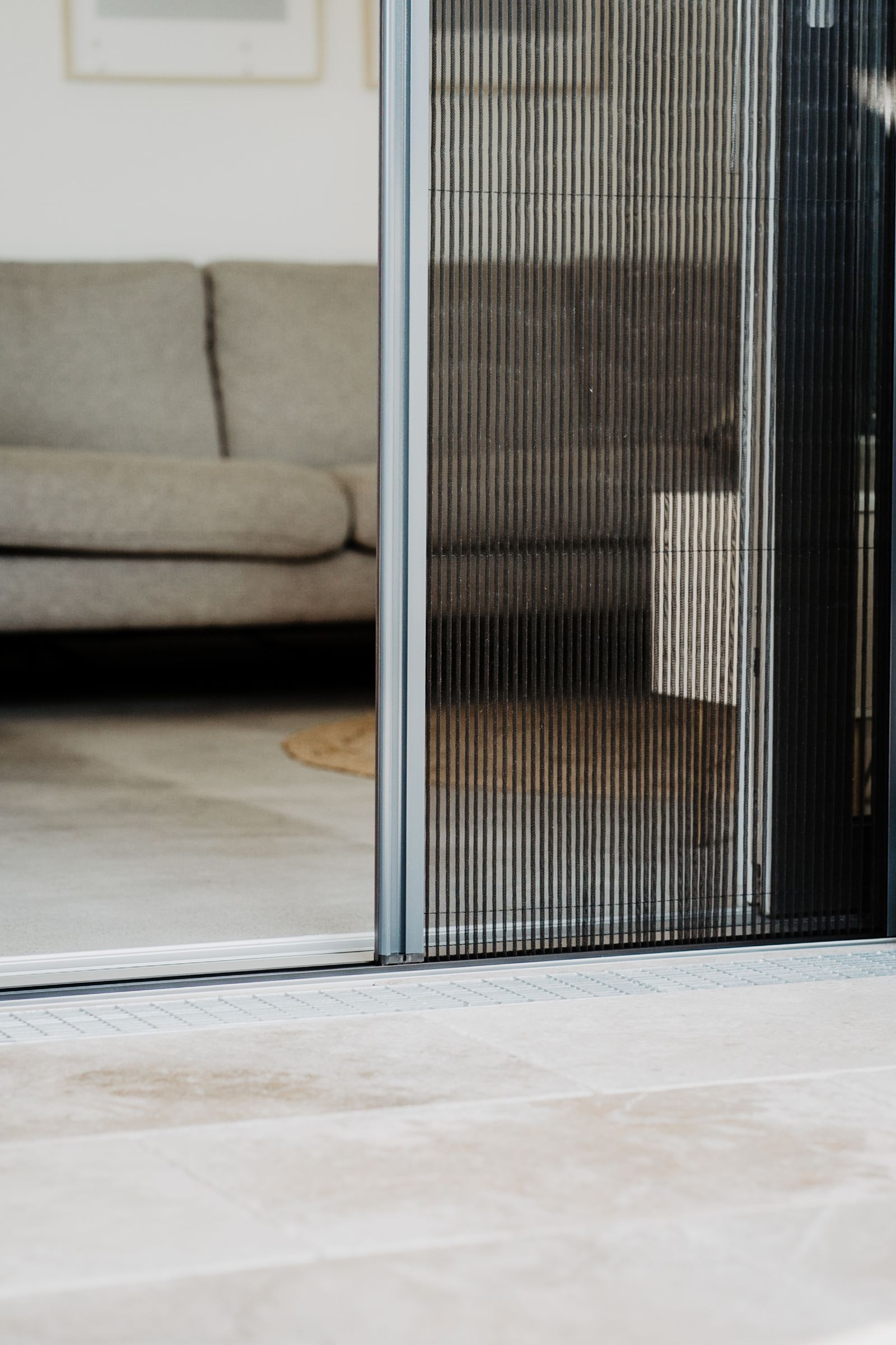 Nahaufnahme einer gefalteten, dunklen, vertikalen Fliegengittertür, die teilweise geschlossen ist