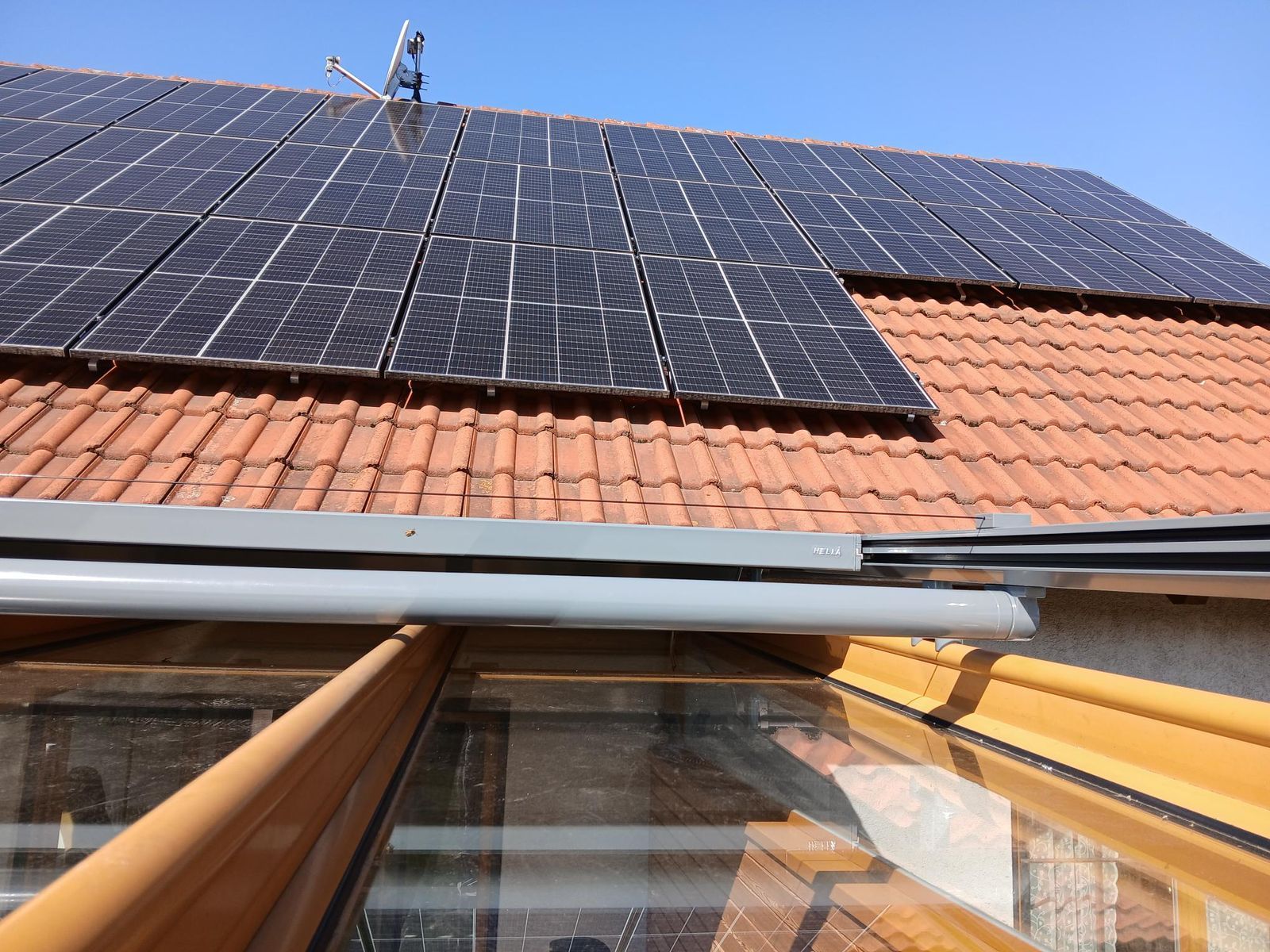 Auf einem mit Terrakotta-Ziegeln gedeckten Dach über dem Glasdach eines Wintergartens mit Solarpaneele installiert.