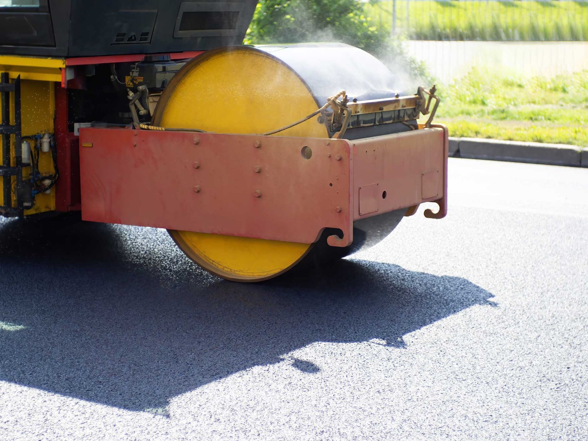 A road roller flattens a road with asphalt.