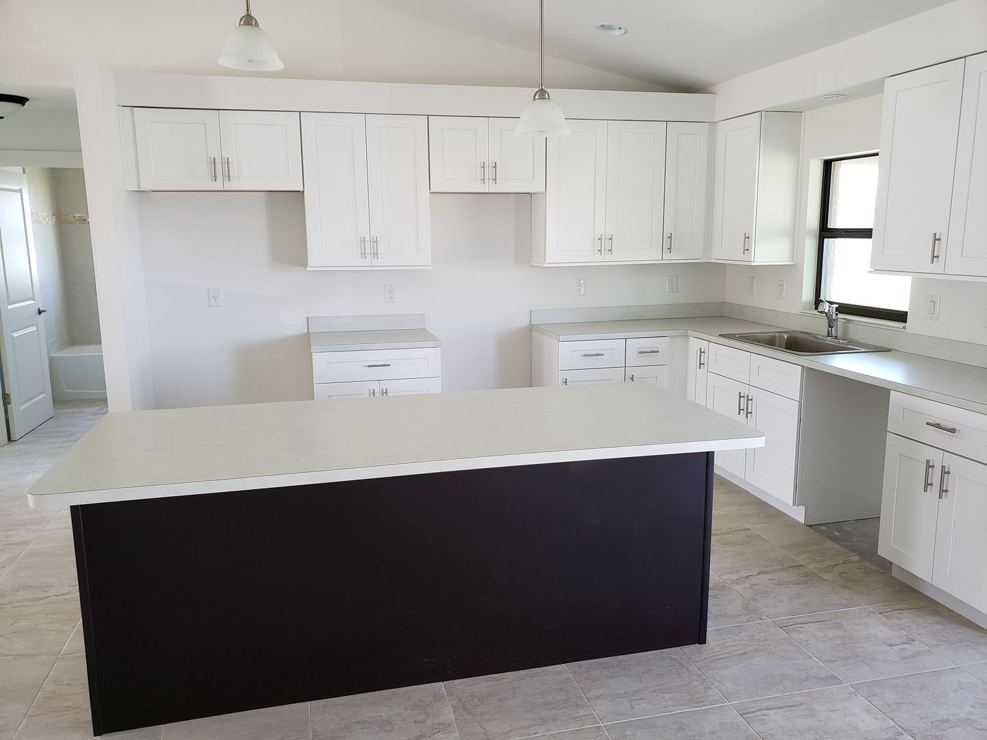 A kitchen with white cabinets and a black island in the middle built by Blue Heron Construction Cape Coral