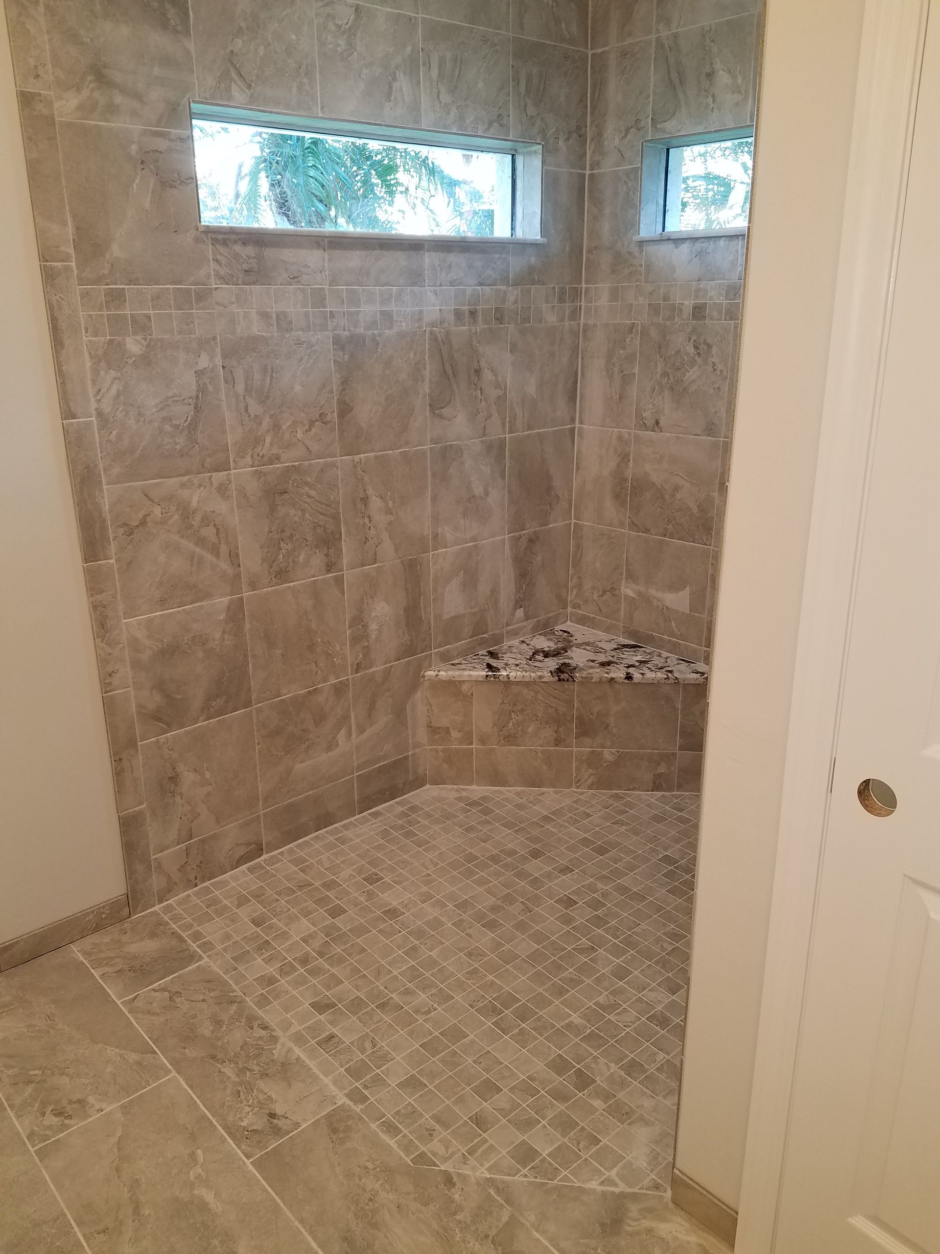 A bathroom with a walk in shower and a window.