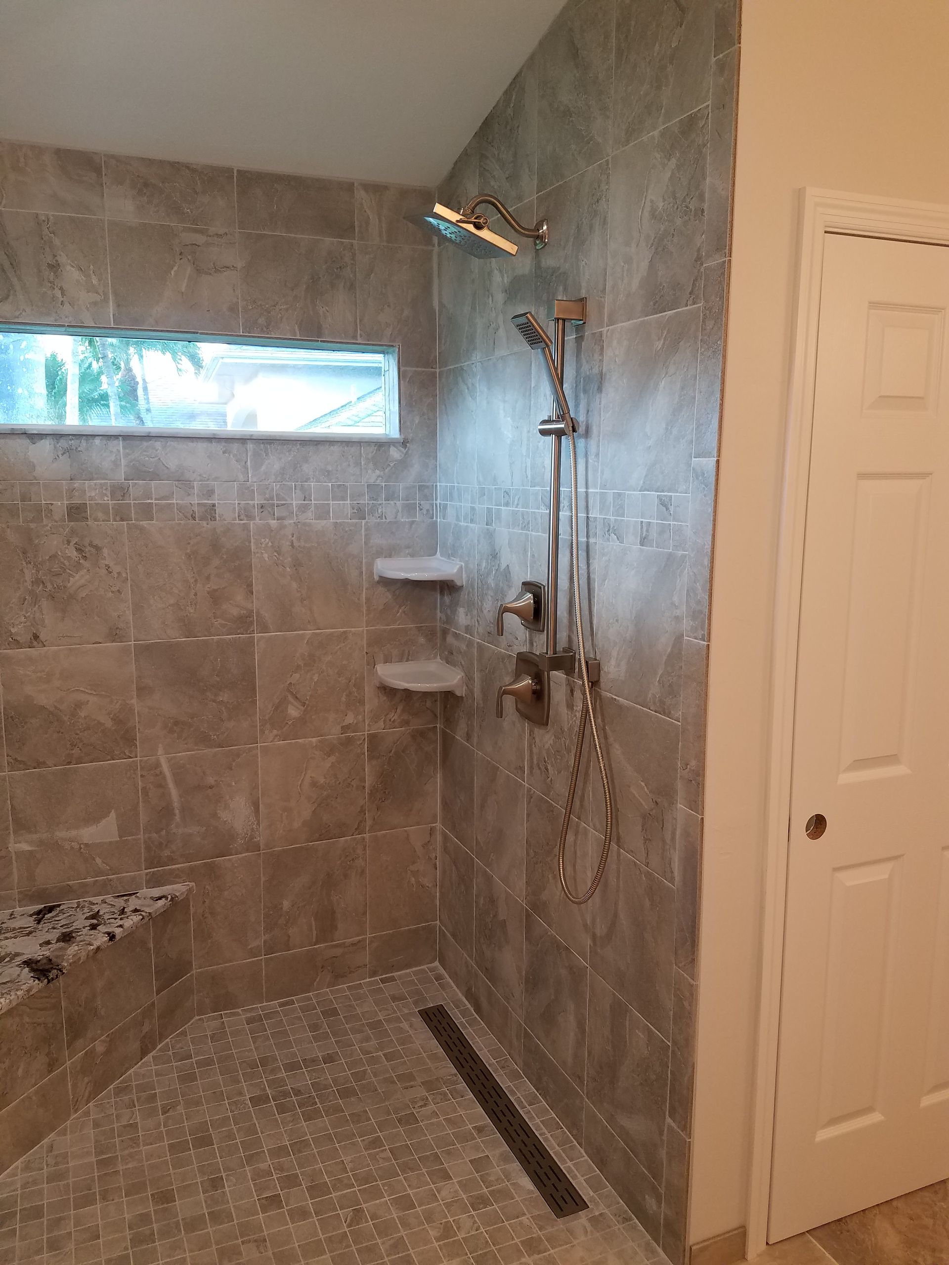 A bathroom with a walk in shower and a window.