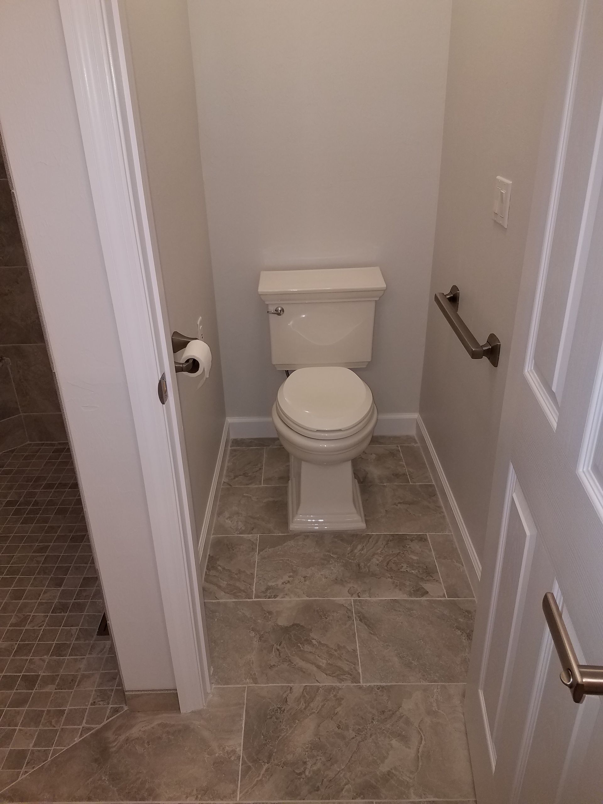 A toilet is sitting in a small bathroom next to a door.