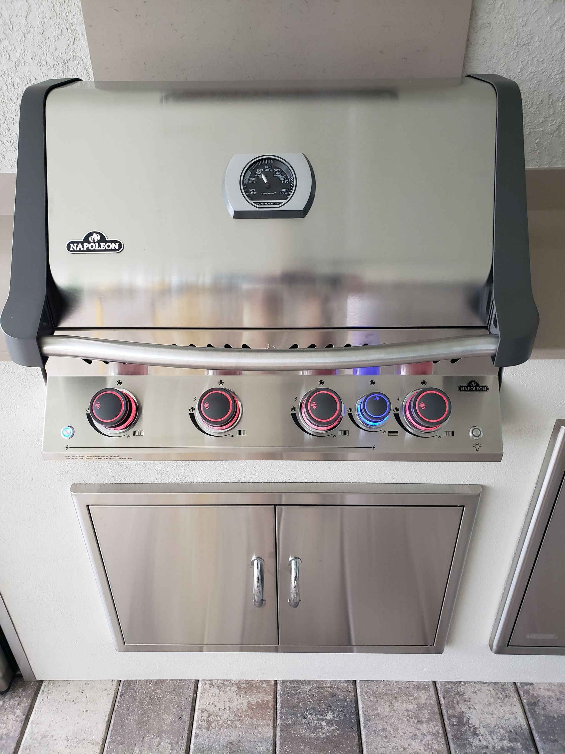 A stainless steel grill is mounted to the wall in a kitchen.