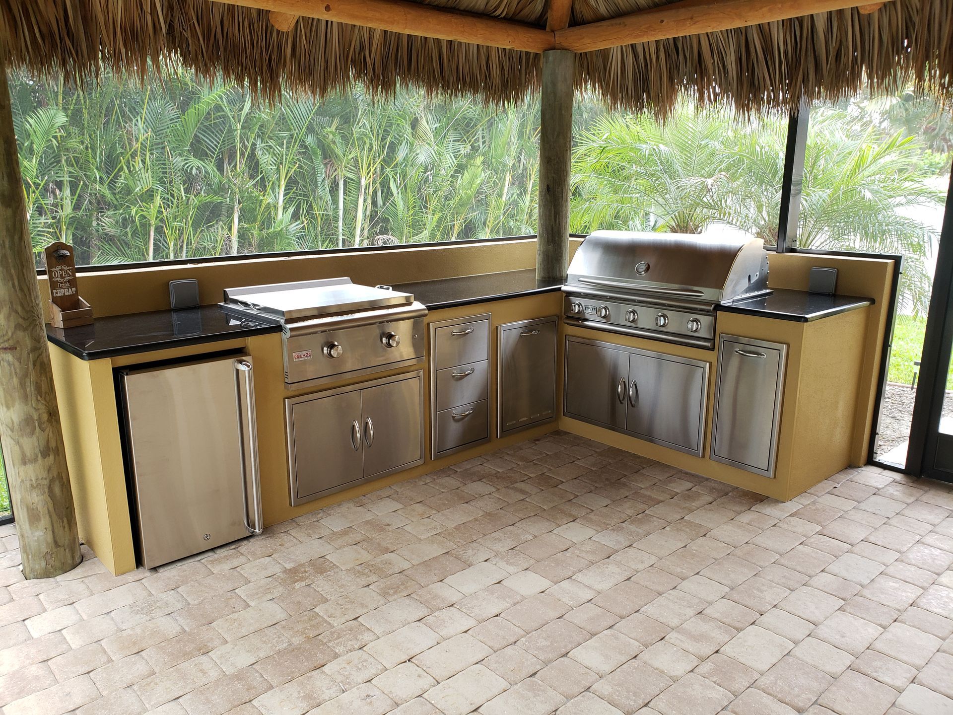 A kitchen with stainless steel appliances and a thatched roof