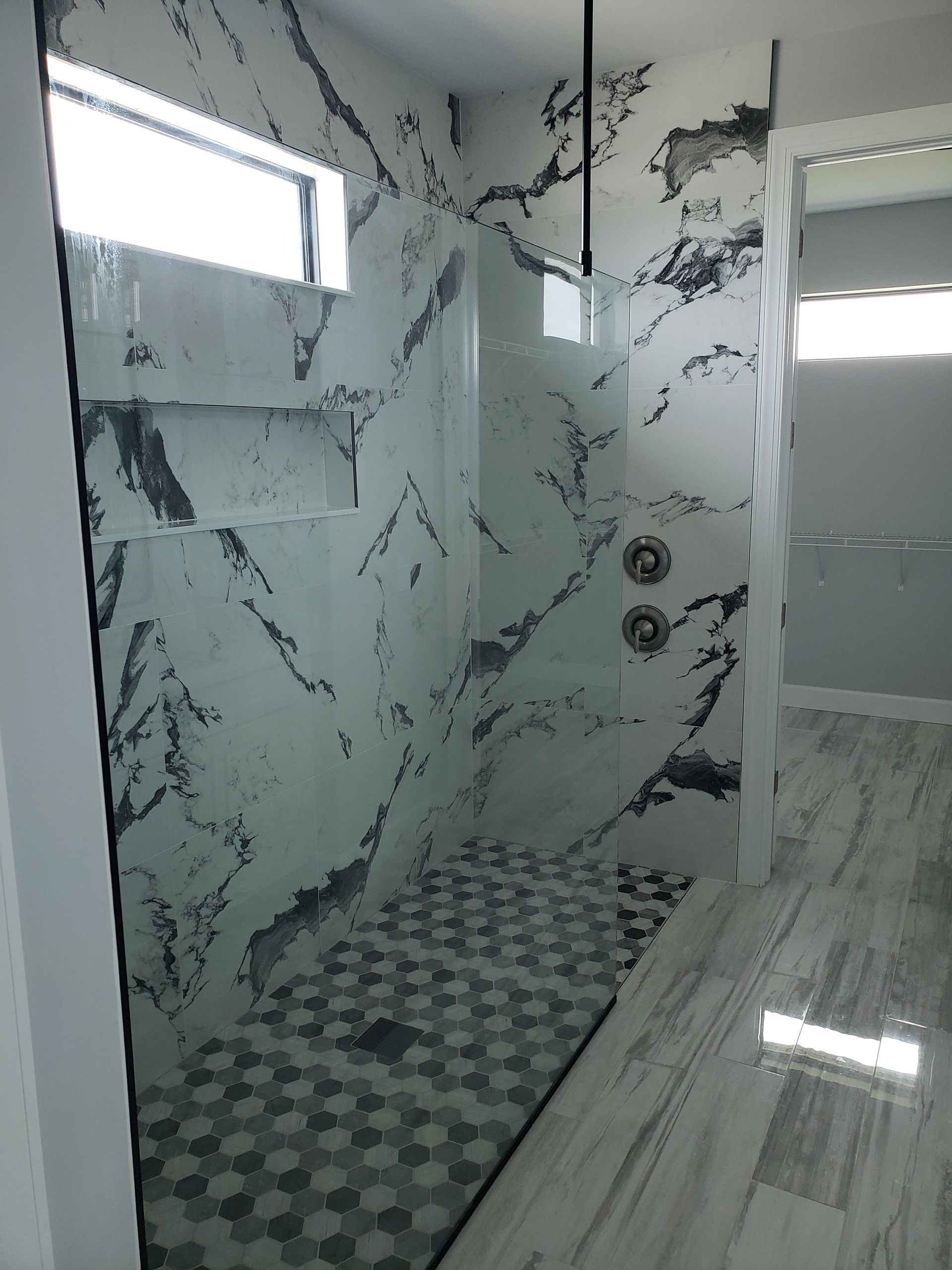 A bathroom with a walk in shower and a marble wall.