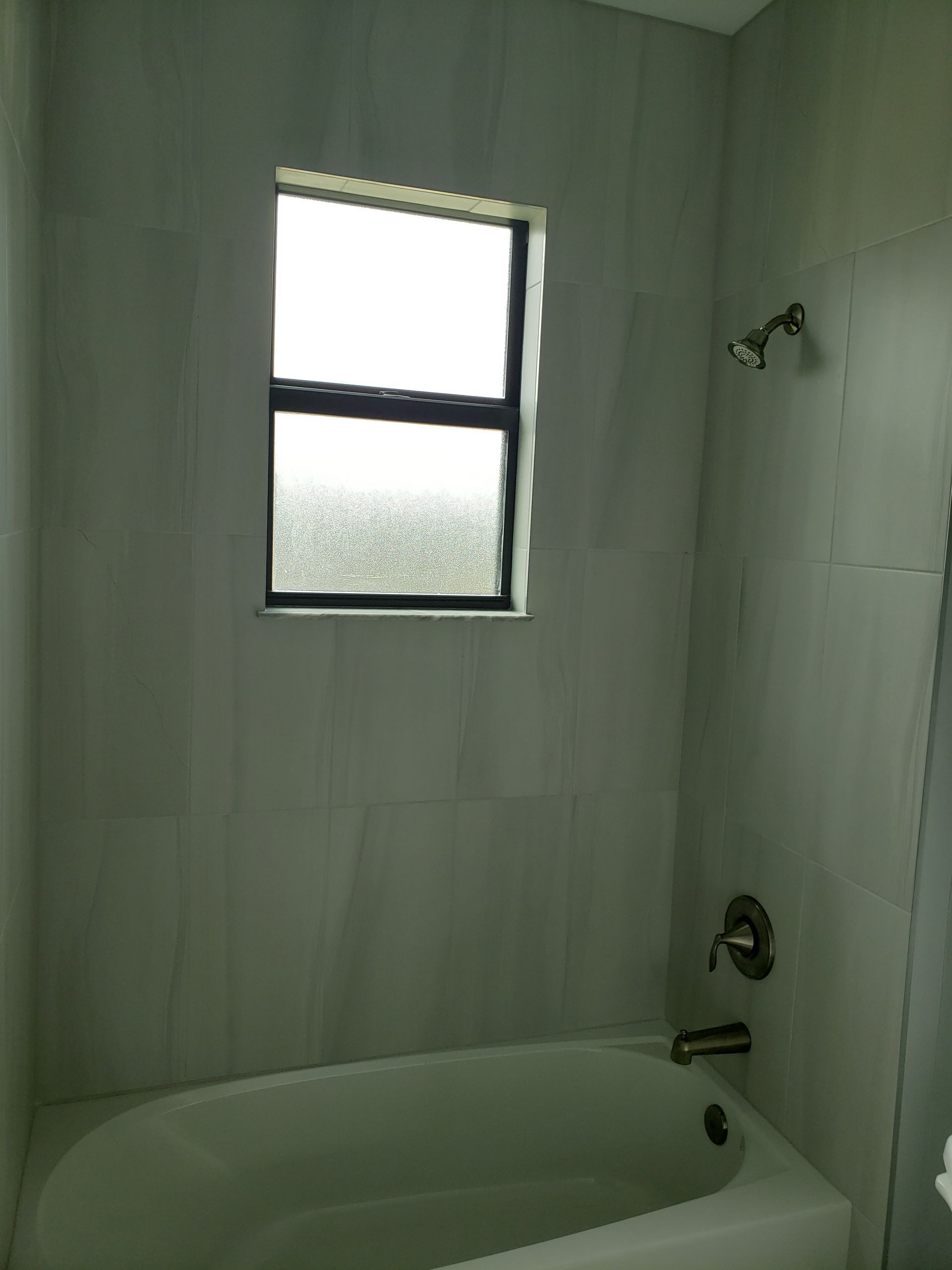 A bathroom with a bathtub and a window.