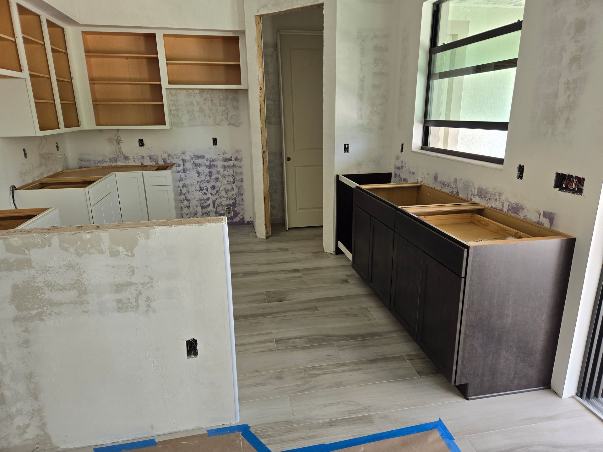 A kitchen under construction with wooden cabinets and a window.