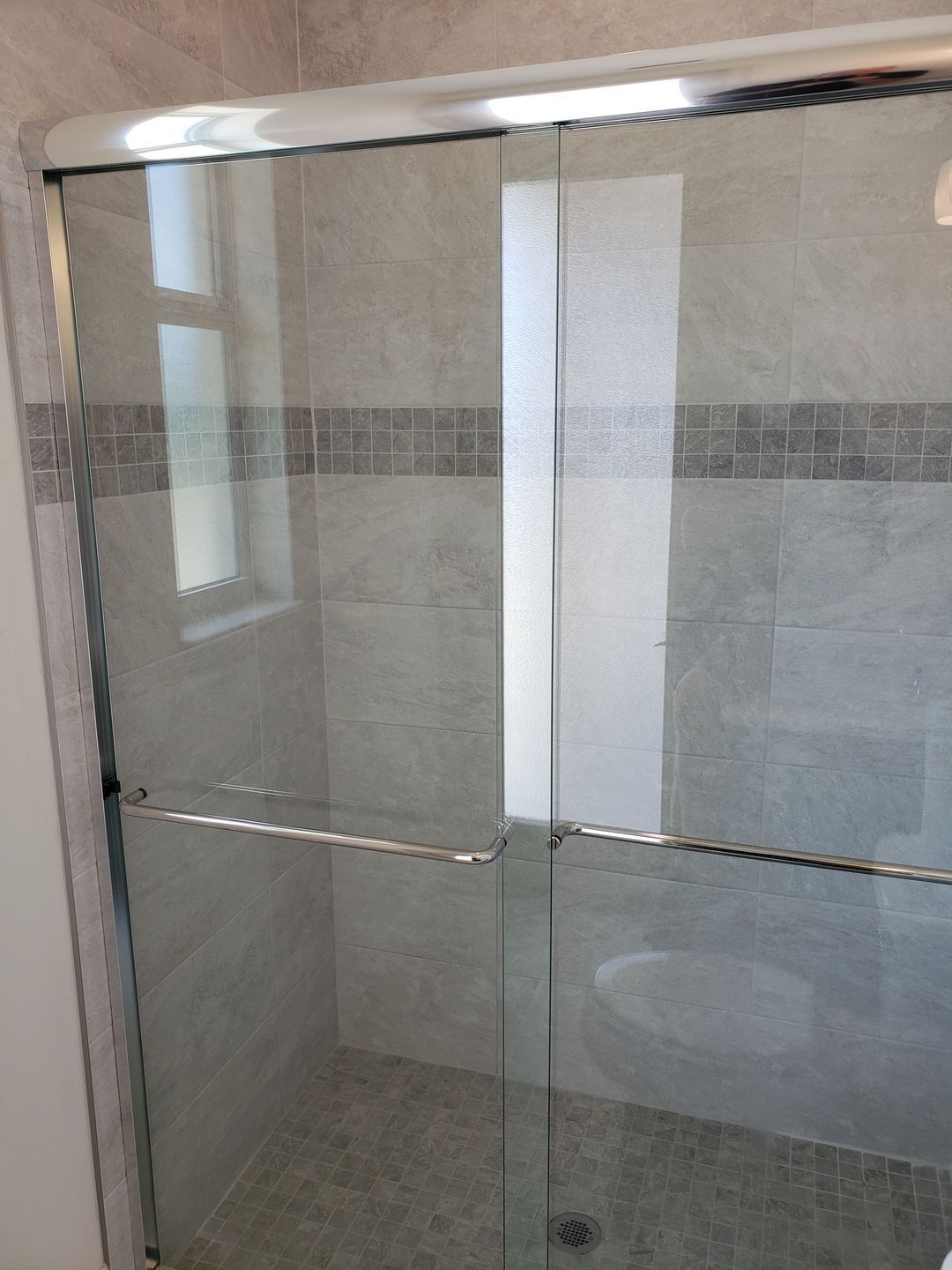 A bathroom with a sliding glass shower door.