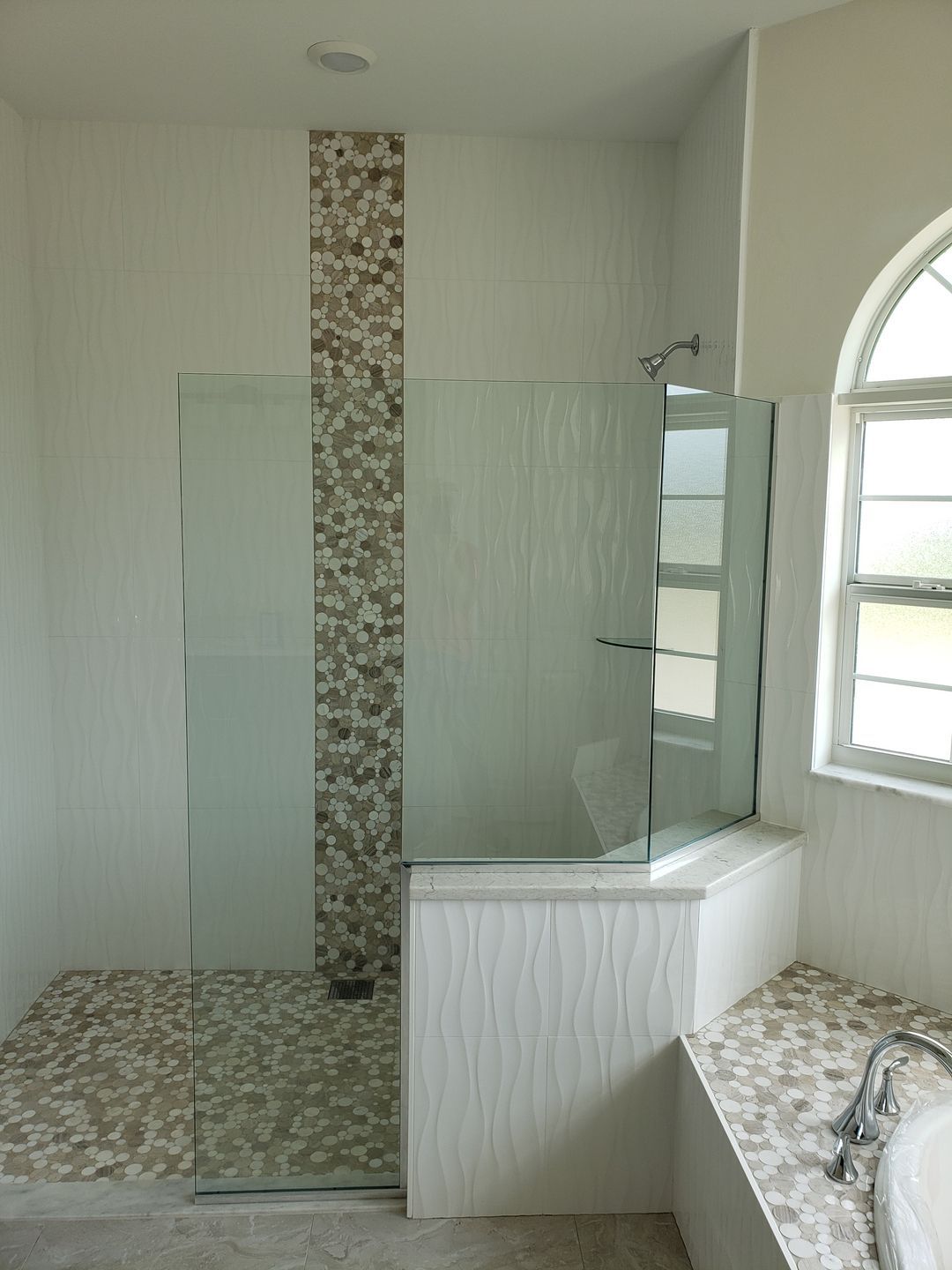 A bathroom with a walk in shower and a window