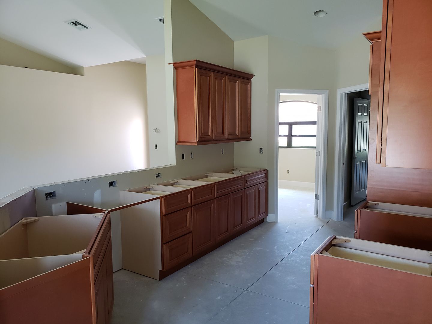 A kitchen under construction with wooden cabinets and boxes on the floor built by Blue Heron Construction Cape Coral