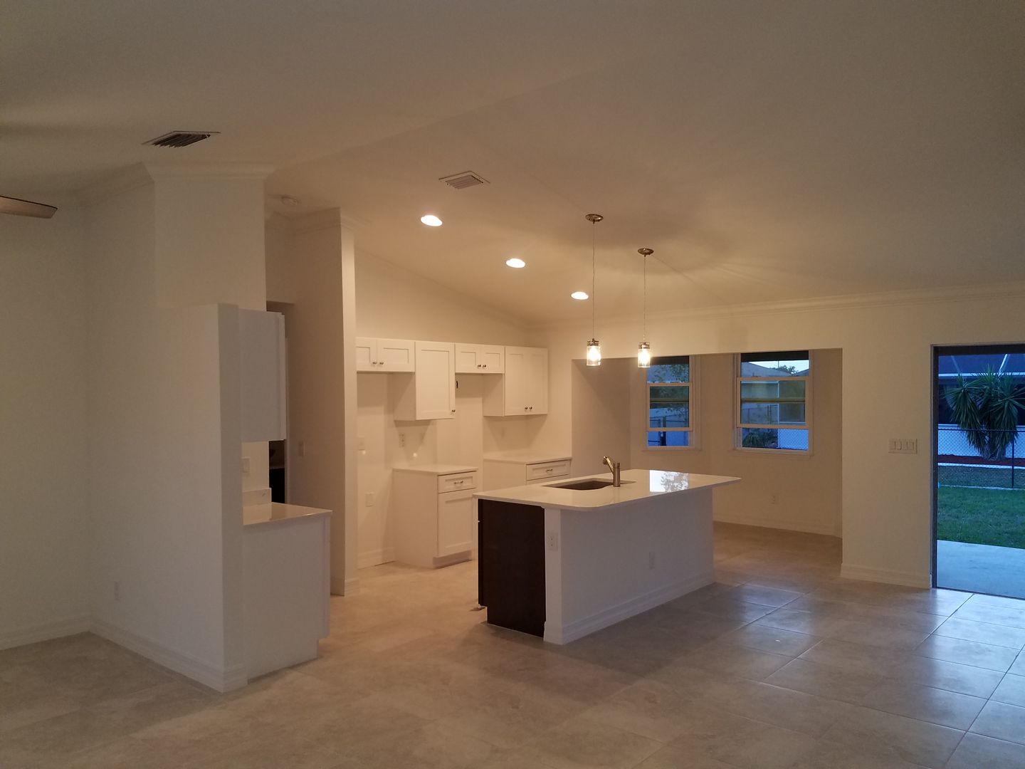 An empty kitchen with white cabinets and a large island built by Blue Heron Construction Cape Coral