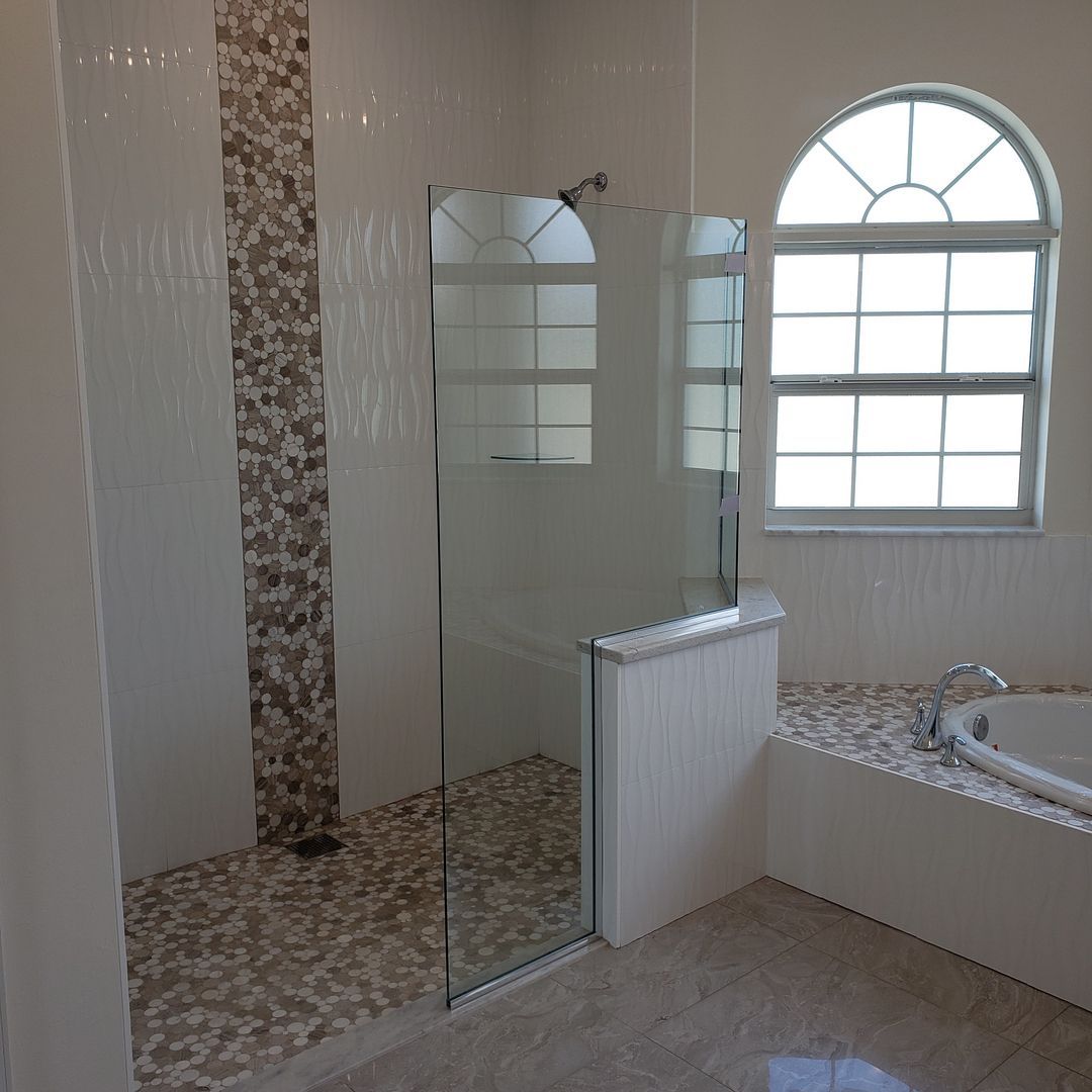 A bathroom with a walk in shower and a tub built by Blue Heron Construction Cape Coral