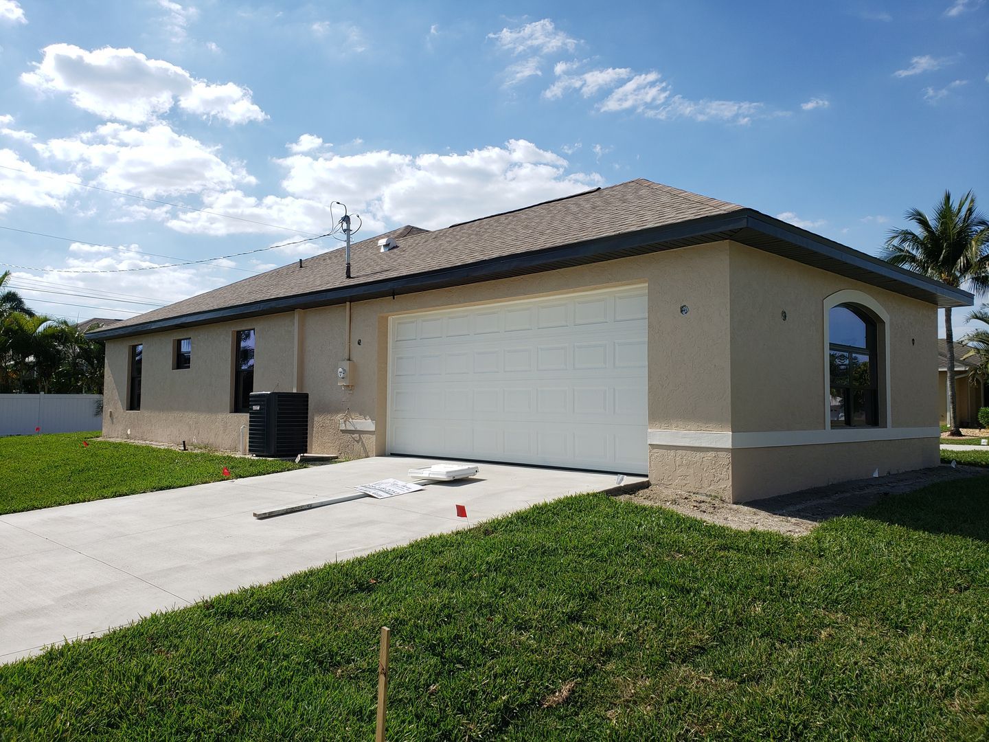 A house with a white garage door is sitting on top of a lush green lawn built by Blue Heron Construction Cape Coral