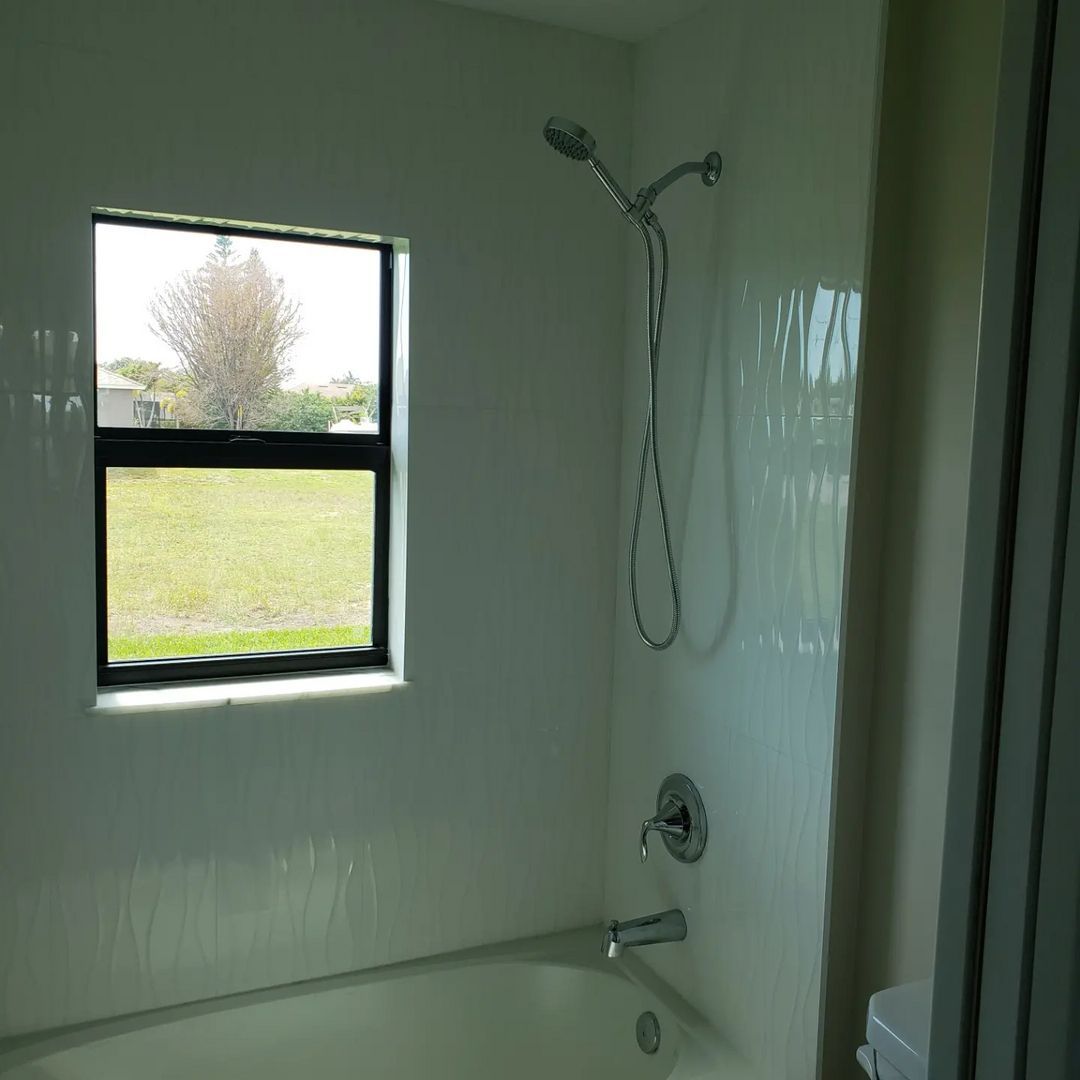 A bathroom with a tub a shower and a window