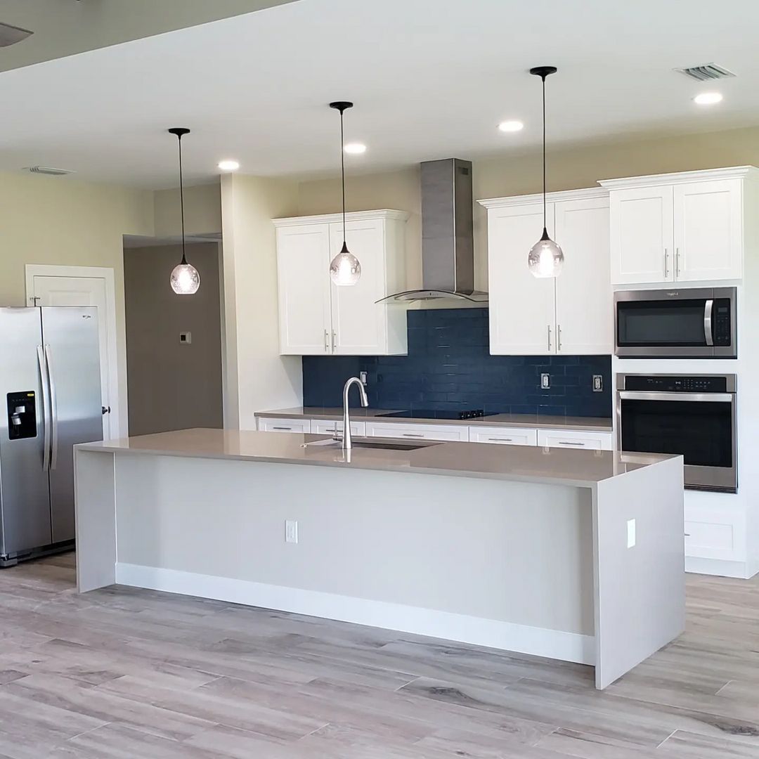 A kitchen with white cabinets and stainless steel appliances built by Blue Heron Construction Cape Coral