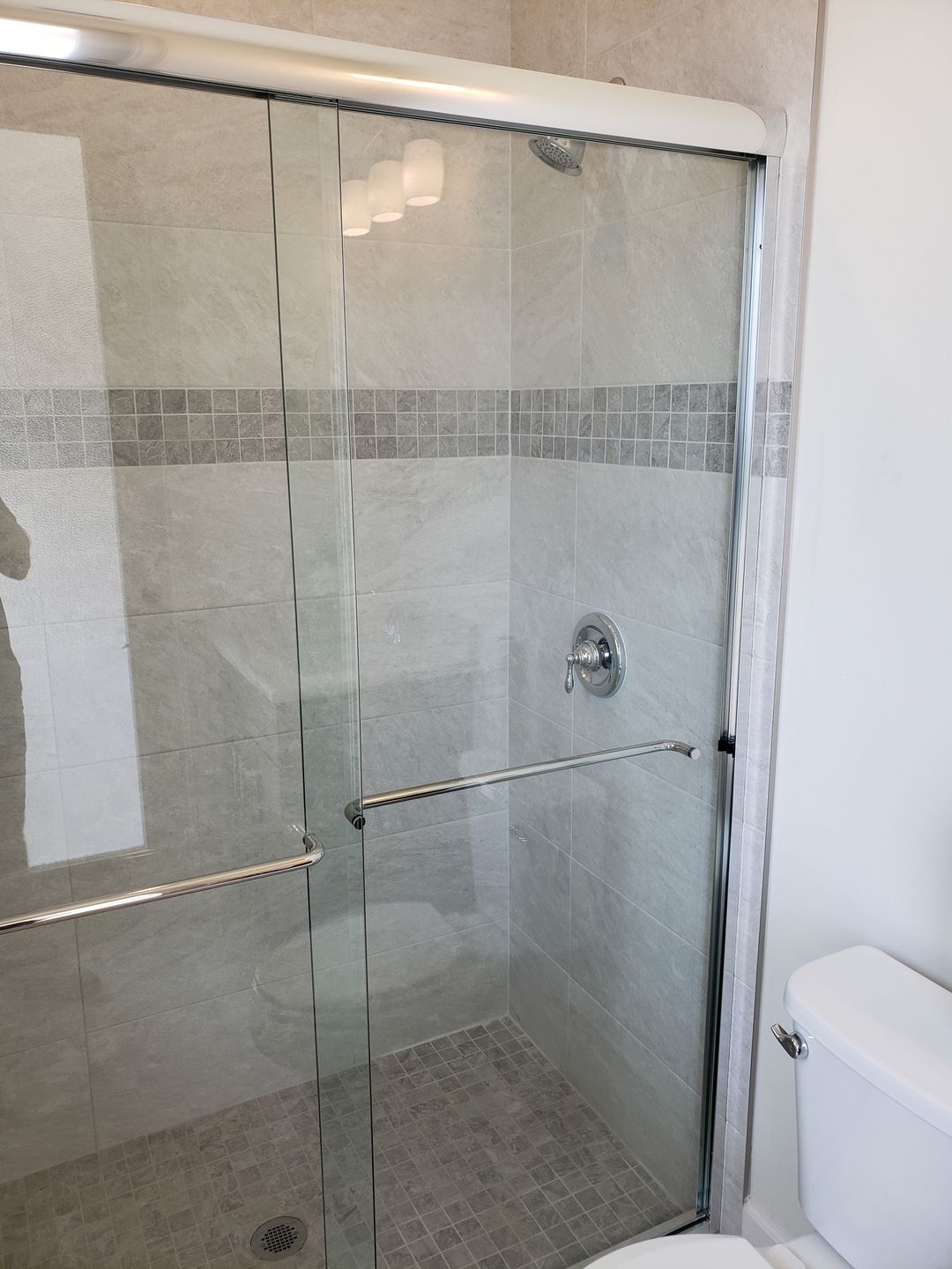 A bathroom with a sliding glass shower door and a toilet