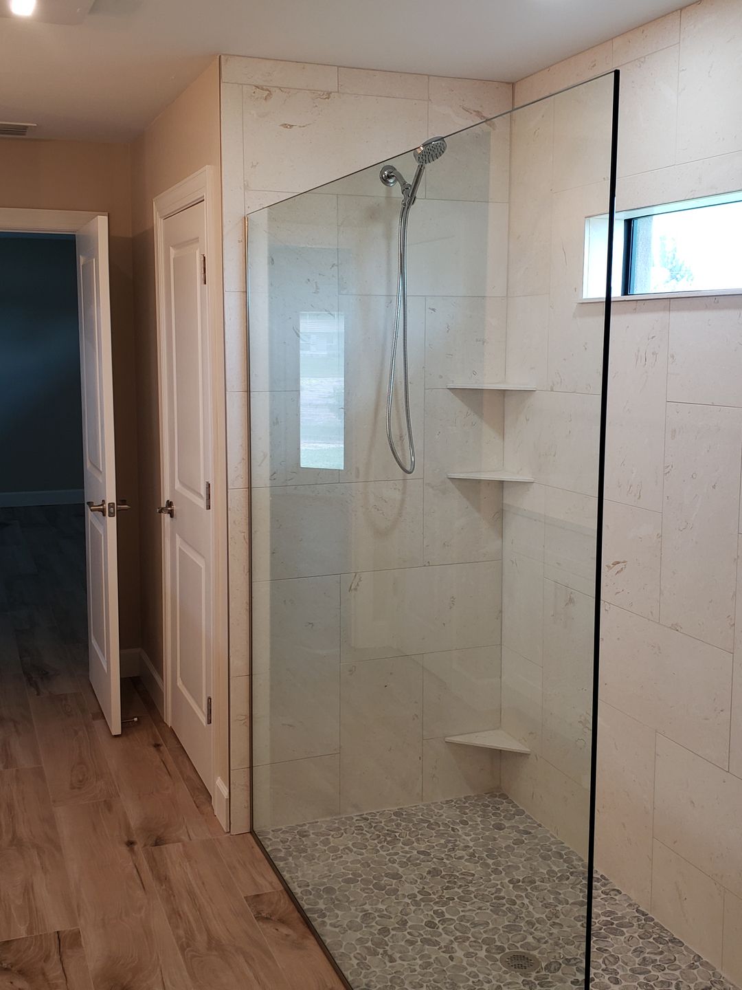A bathroom with a walk in shower with a glass door.