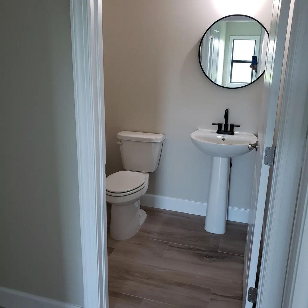 A bathroom with a toilet , sink and mirror.